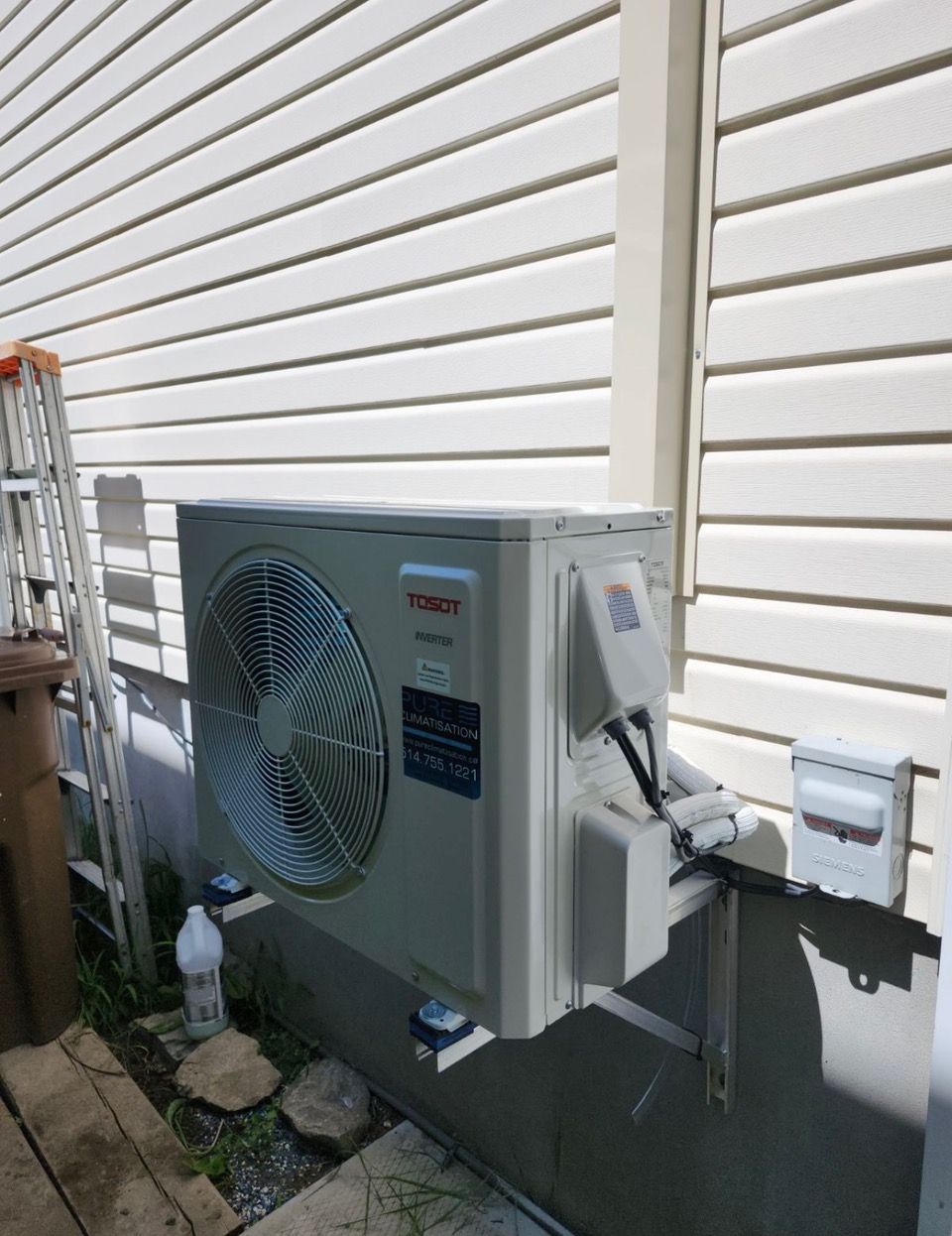 Un grand climatiseur est monté sur le côté d'une maison.