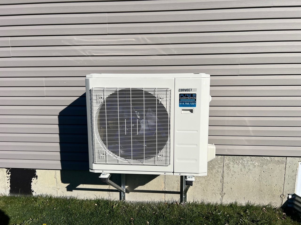 Un climatiseur blanc est monté sur le côté d'une maison.