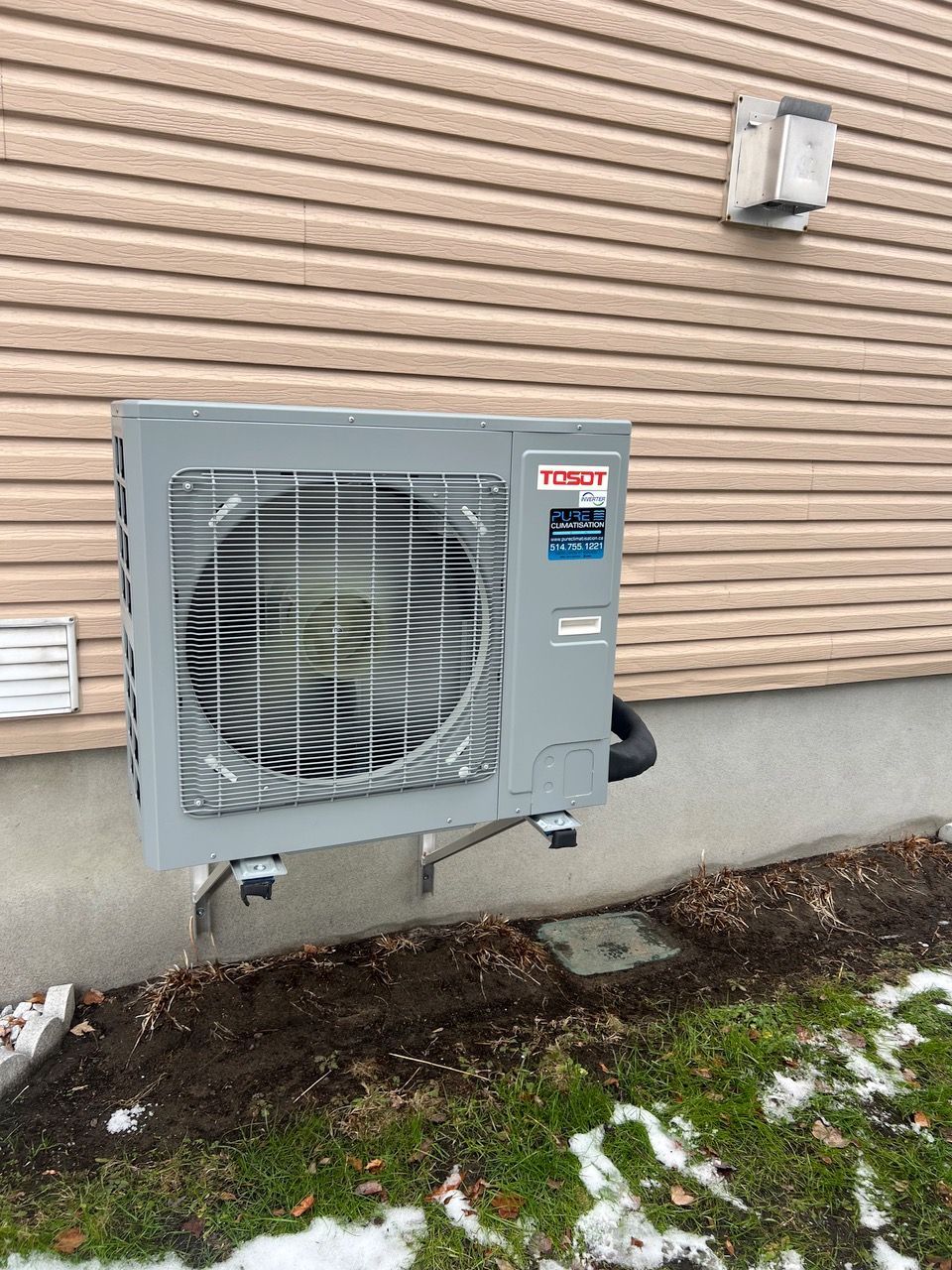 Un grand climatiseur est monté sur le côté d'une maison.