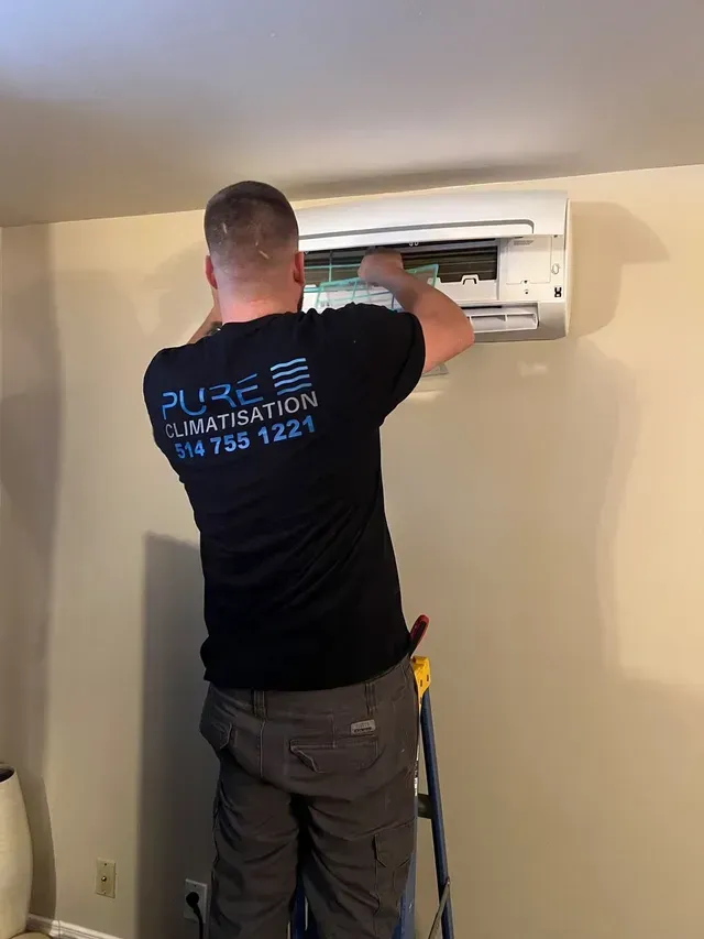 Un homme est debout sur une échelle et travaille sur un climatiseur.