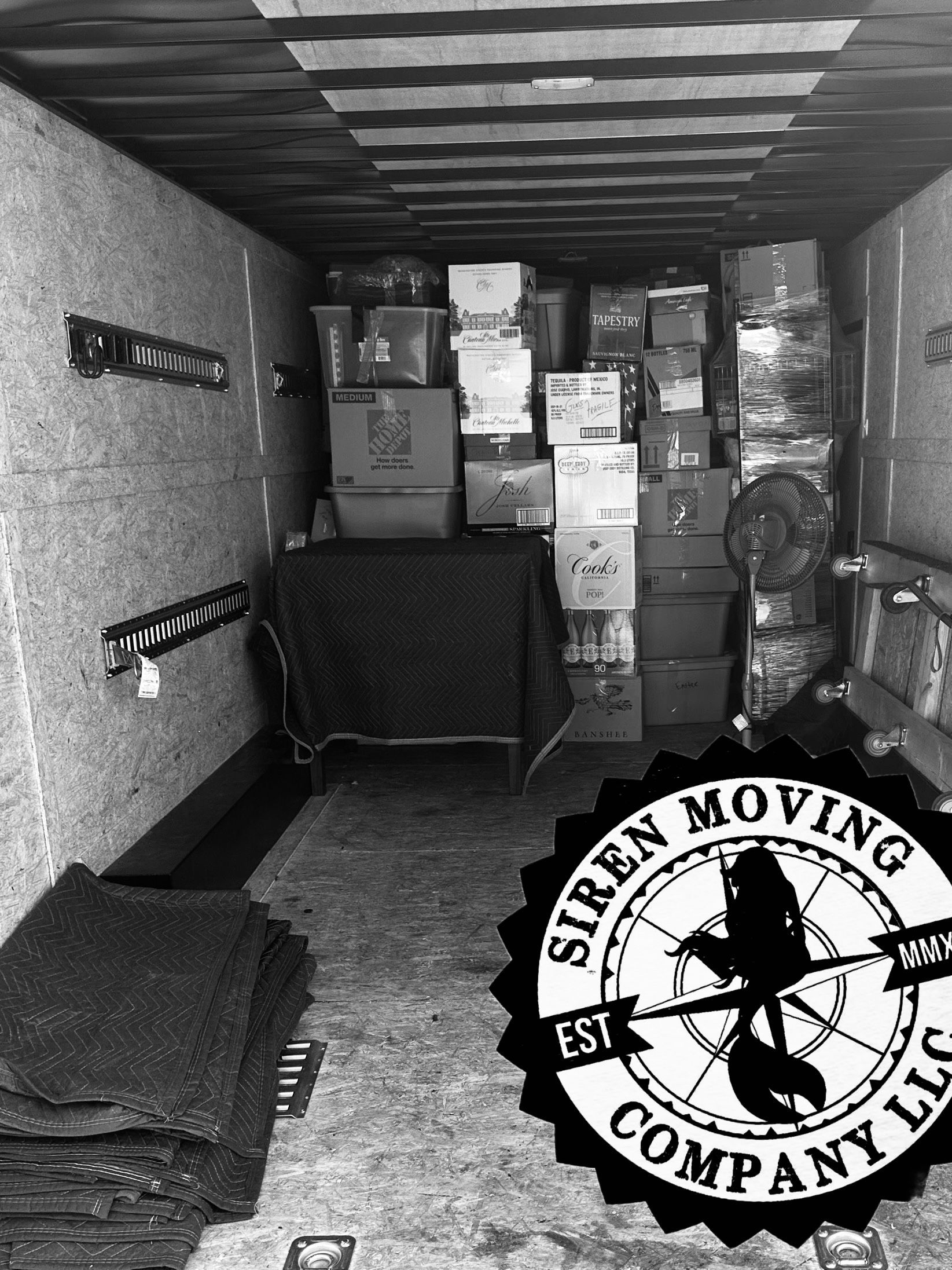 Interior of a truck loaded with packed boxes; Siren Moving Company logo.