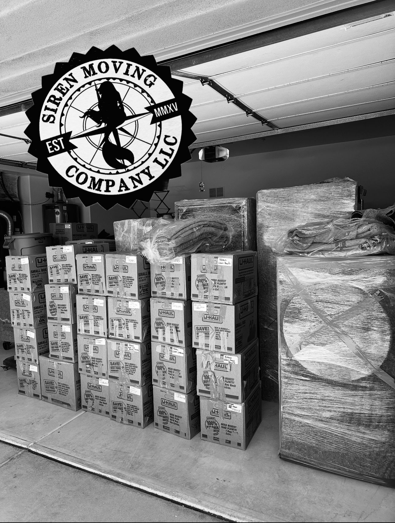 Boxes stacked, wrapped items, and a Siren Moving Company logo. Inside a garage or storage area.
