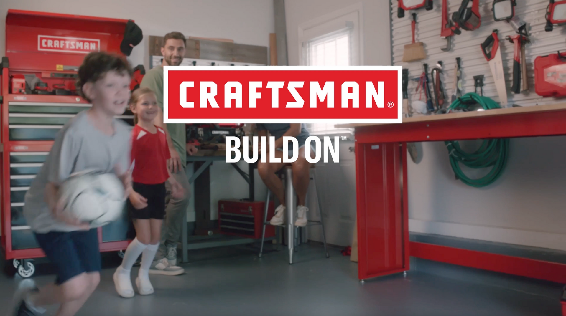 Craftsman logo over a family in a red-themed garage. Children play soccer; father and mother watch.