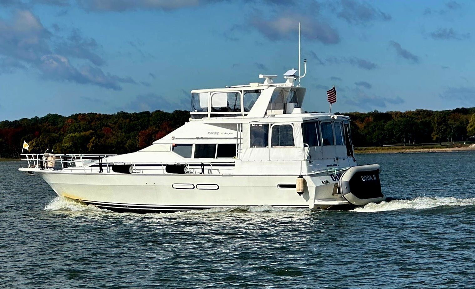 A white boat is parked on a trailer in a gravel lot.