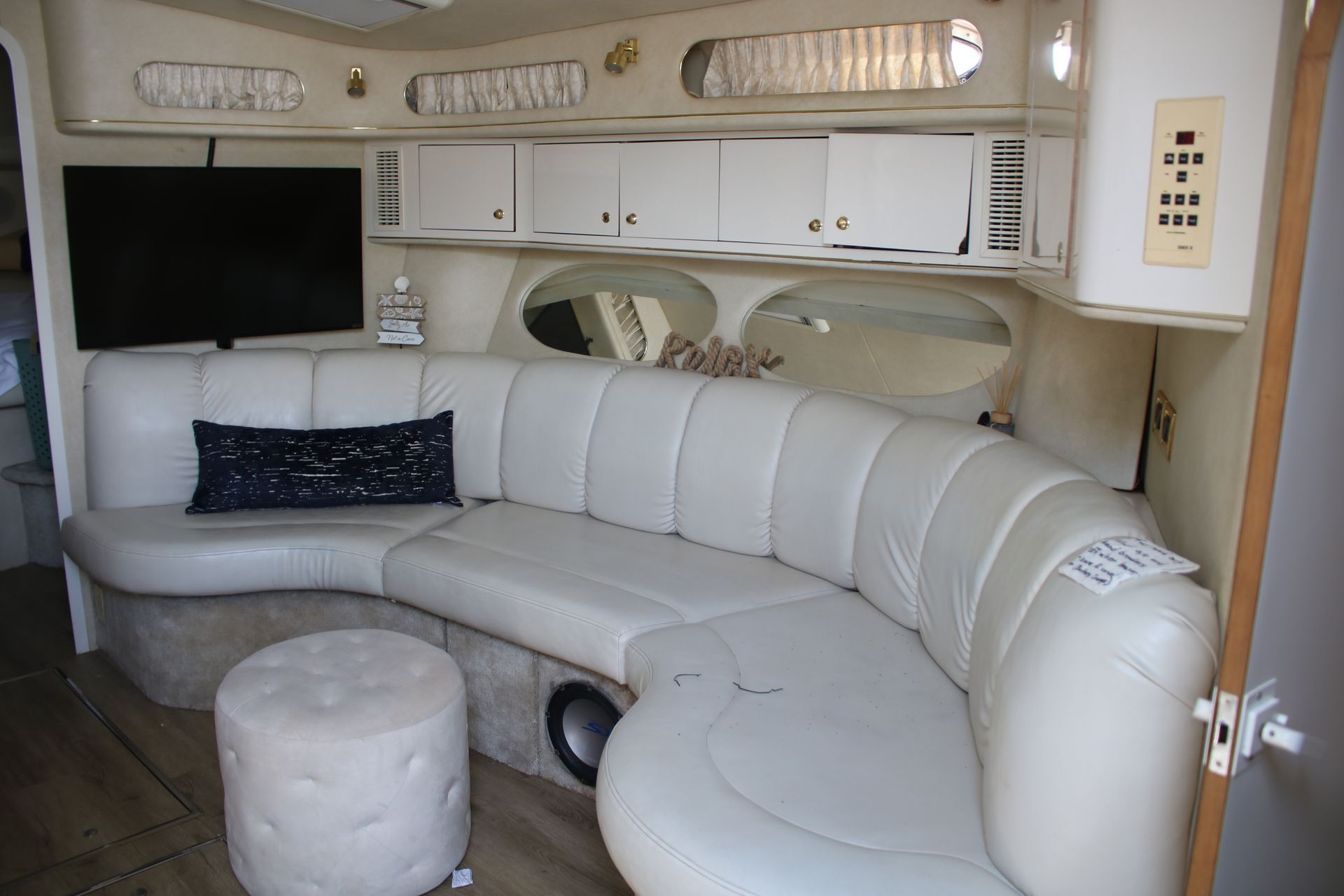 A living room with a couch , ottoman , and television.