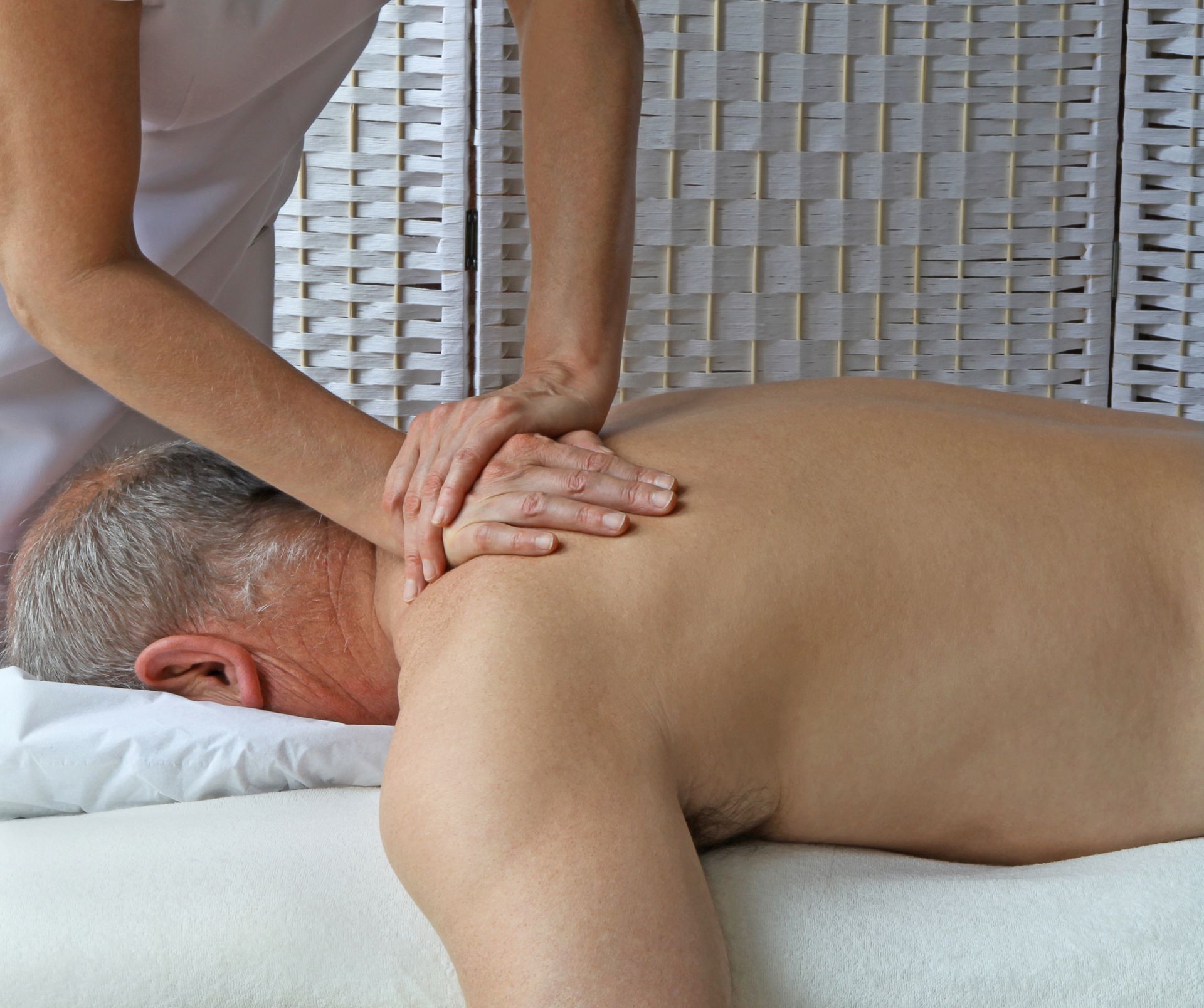A man is laying on a bed getting a massage from a woman.