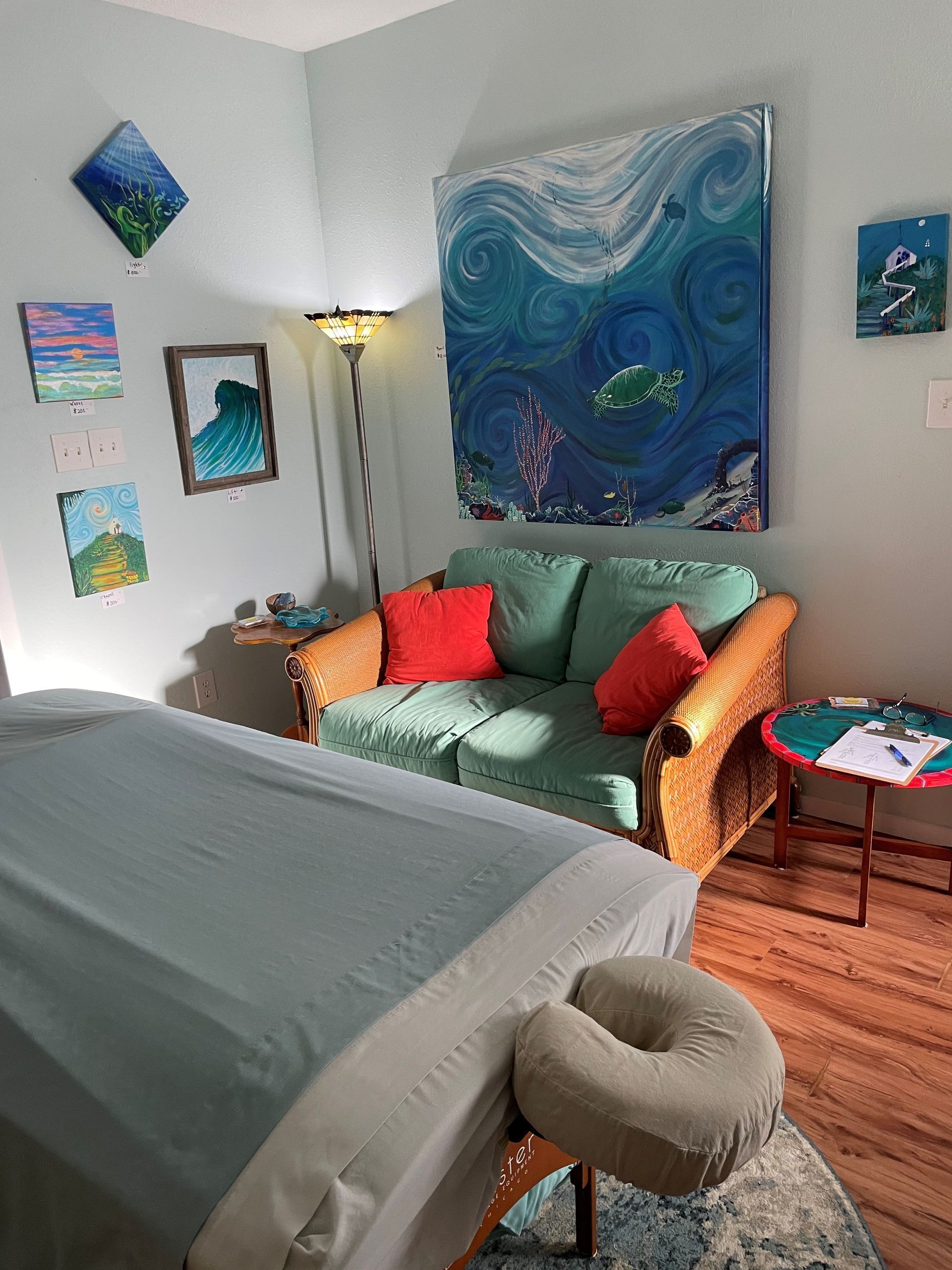 A massage table in a room with a couch and a painting on the wall.