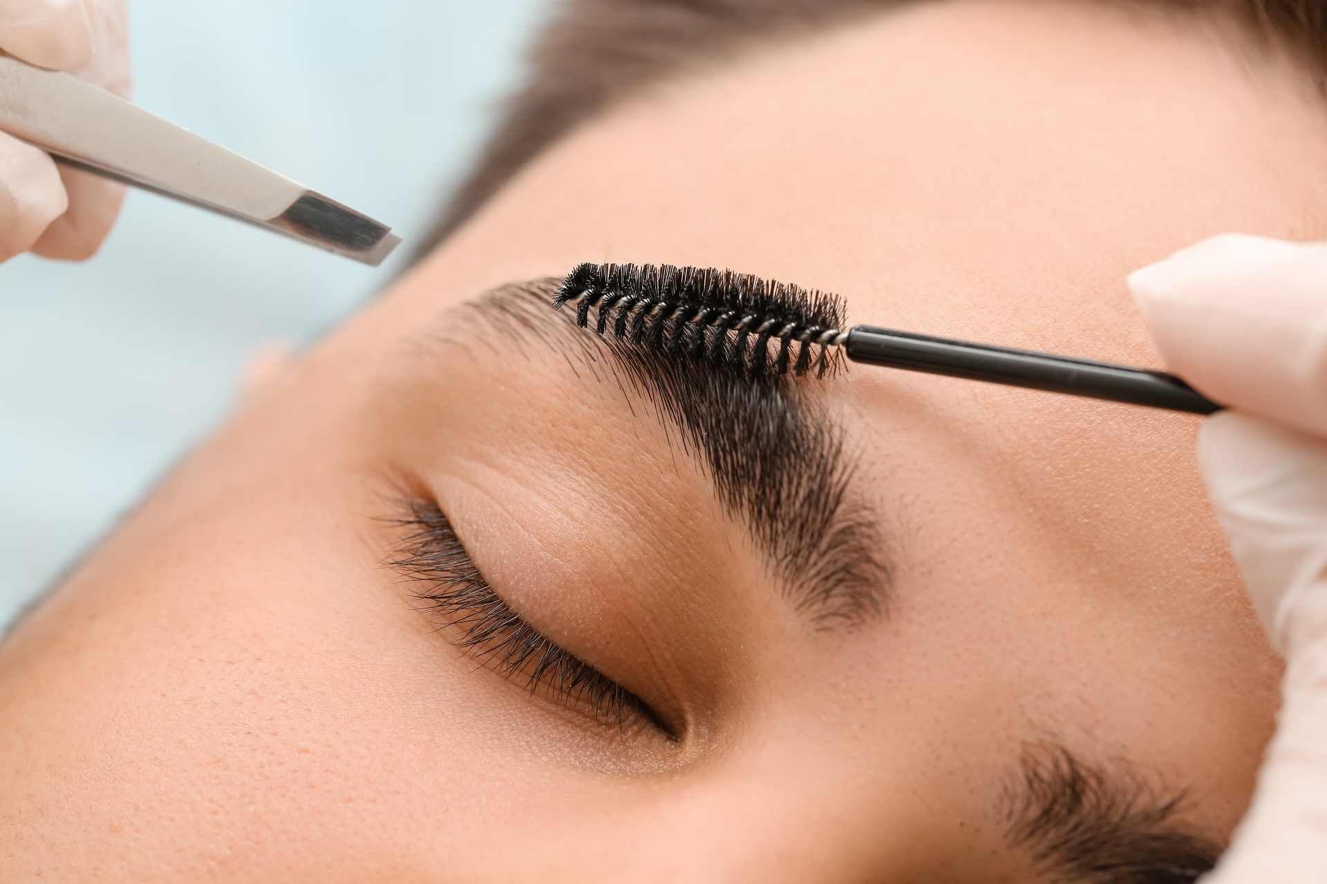 A woman receiving eyebrow shaping from an expert cosmetician near Lexington, Kentucky (KY)