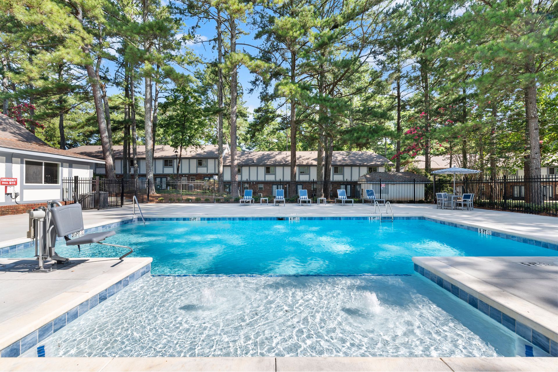 Pool at apartment complex, blue water, wheelchair lift, lounge chairs, tall trees in background at The Arbors at Smyrna, offers apartments near The Battery in Smyrna, GA.