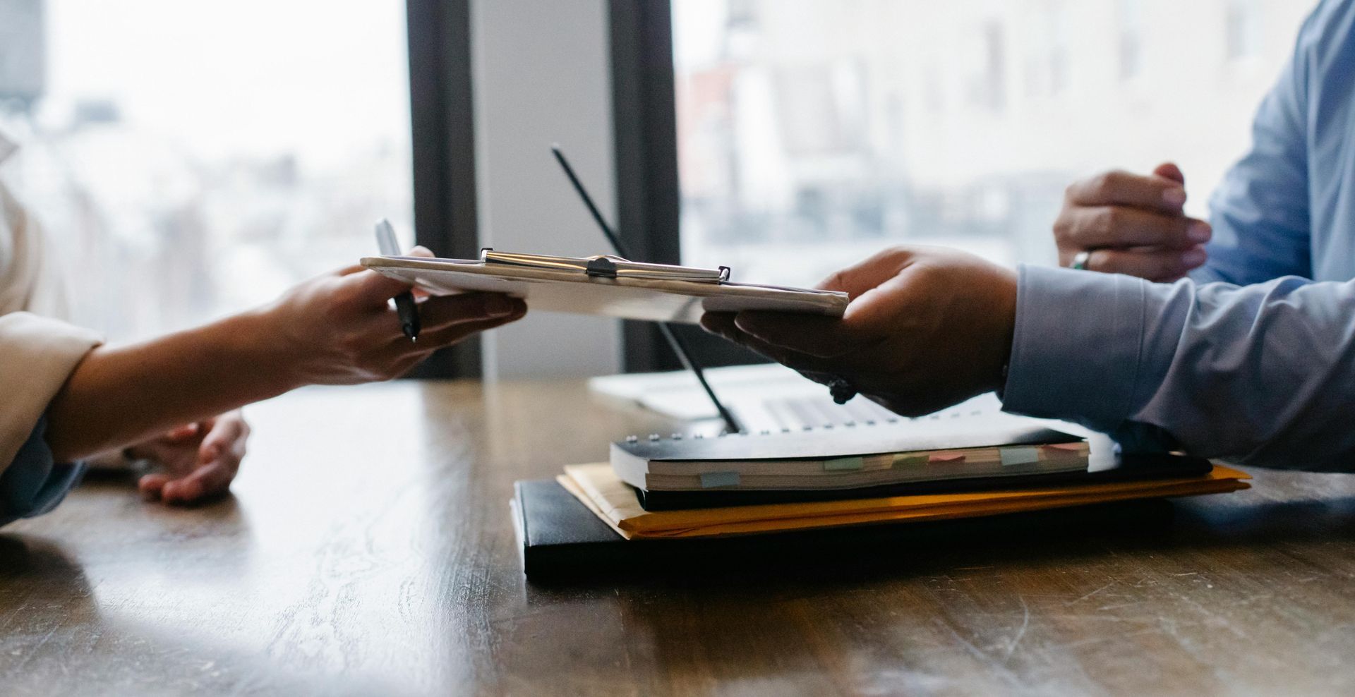 A man and a woman are sitting at a table holding a clipboard.