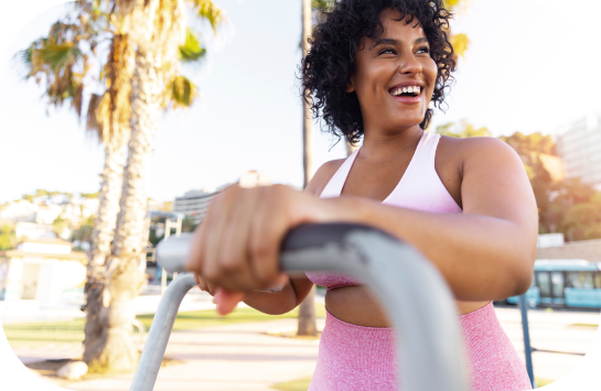 Uma mulher está sorrindo enquanto anda de bicicleta ergométrica em um parque.