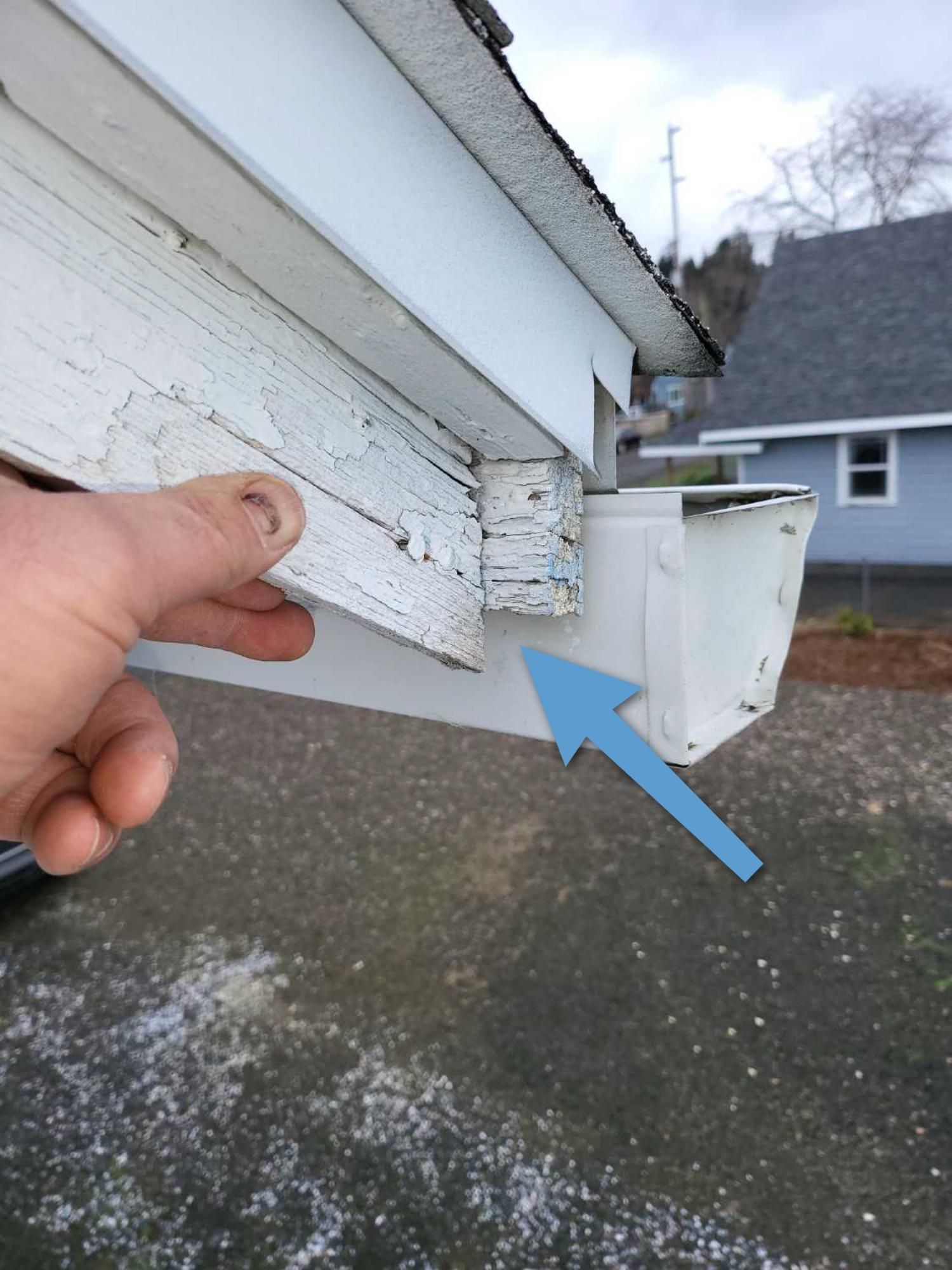 A person is holding a white gutter with an arrow pointing to it.