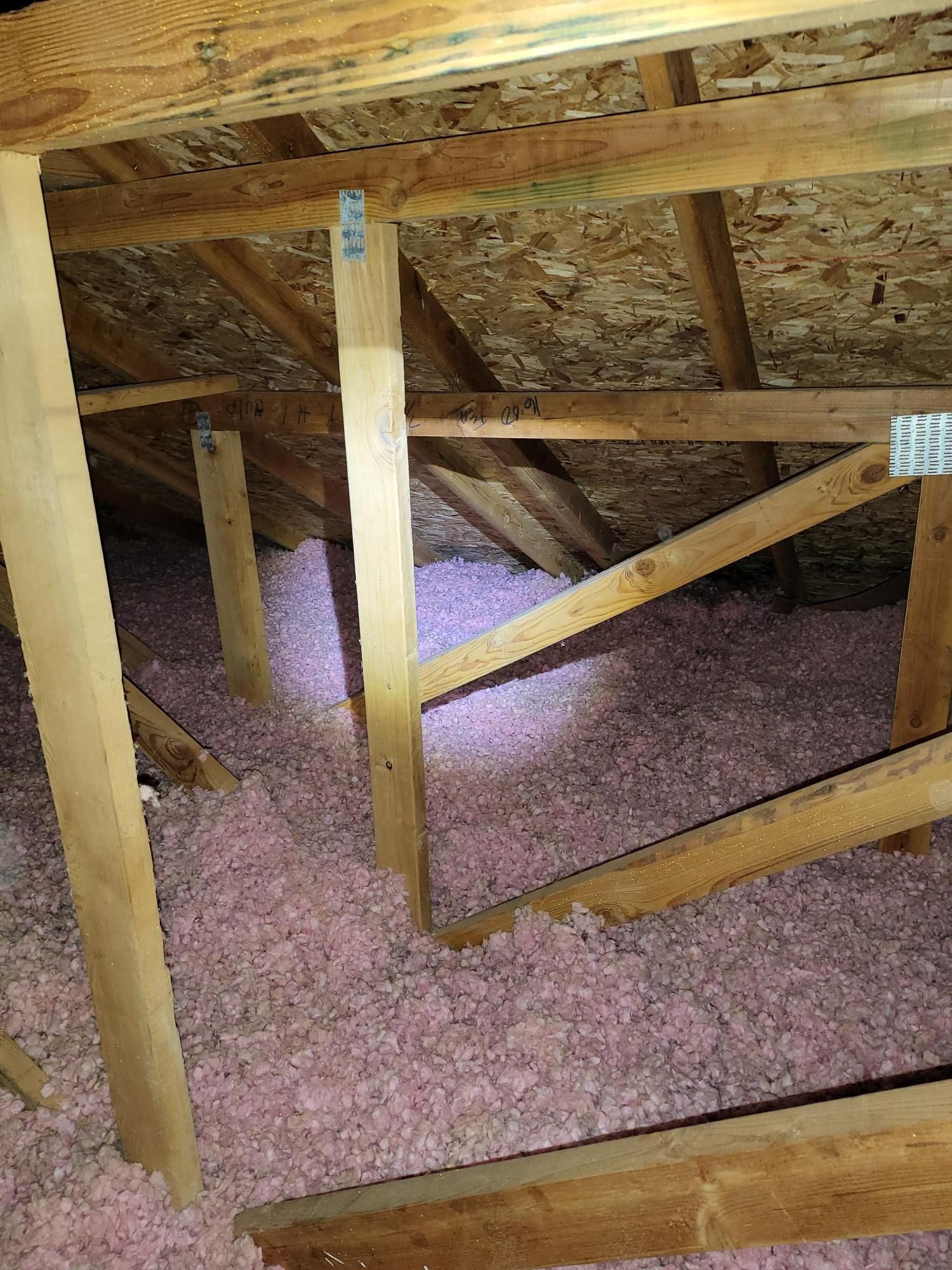 There is a lot of pink insulation in the attic of a house.