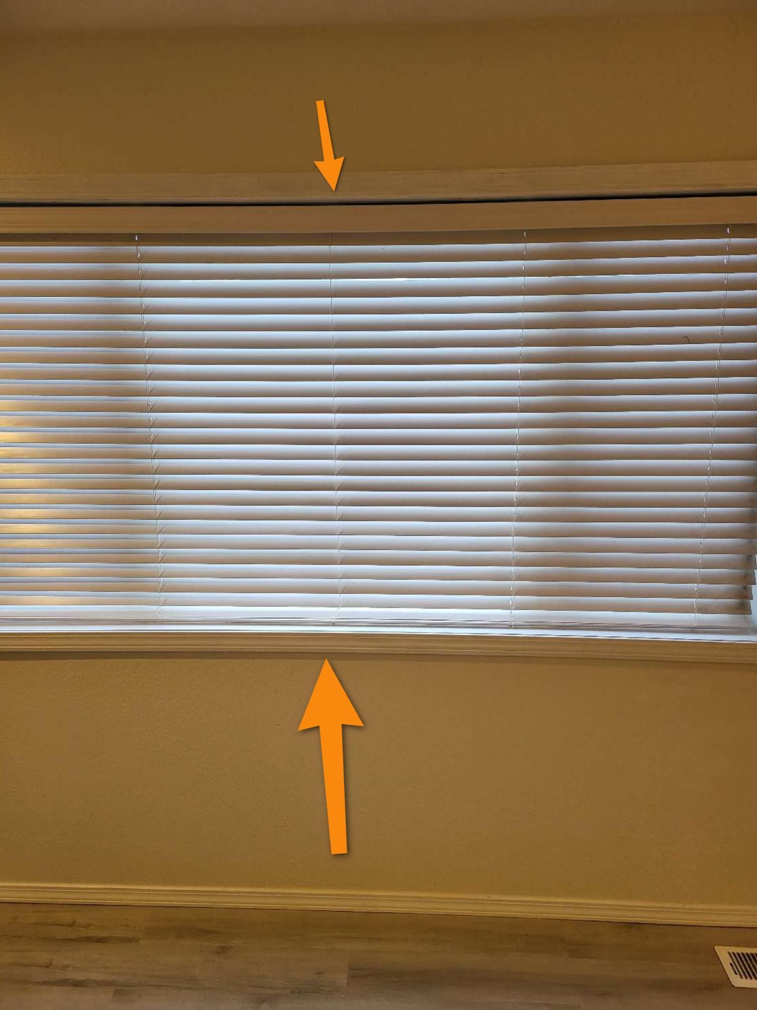 A window with blinds and an orange arrow pointing up and down.