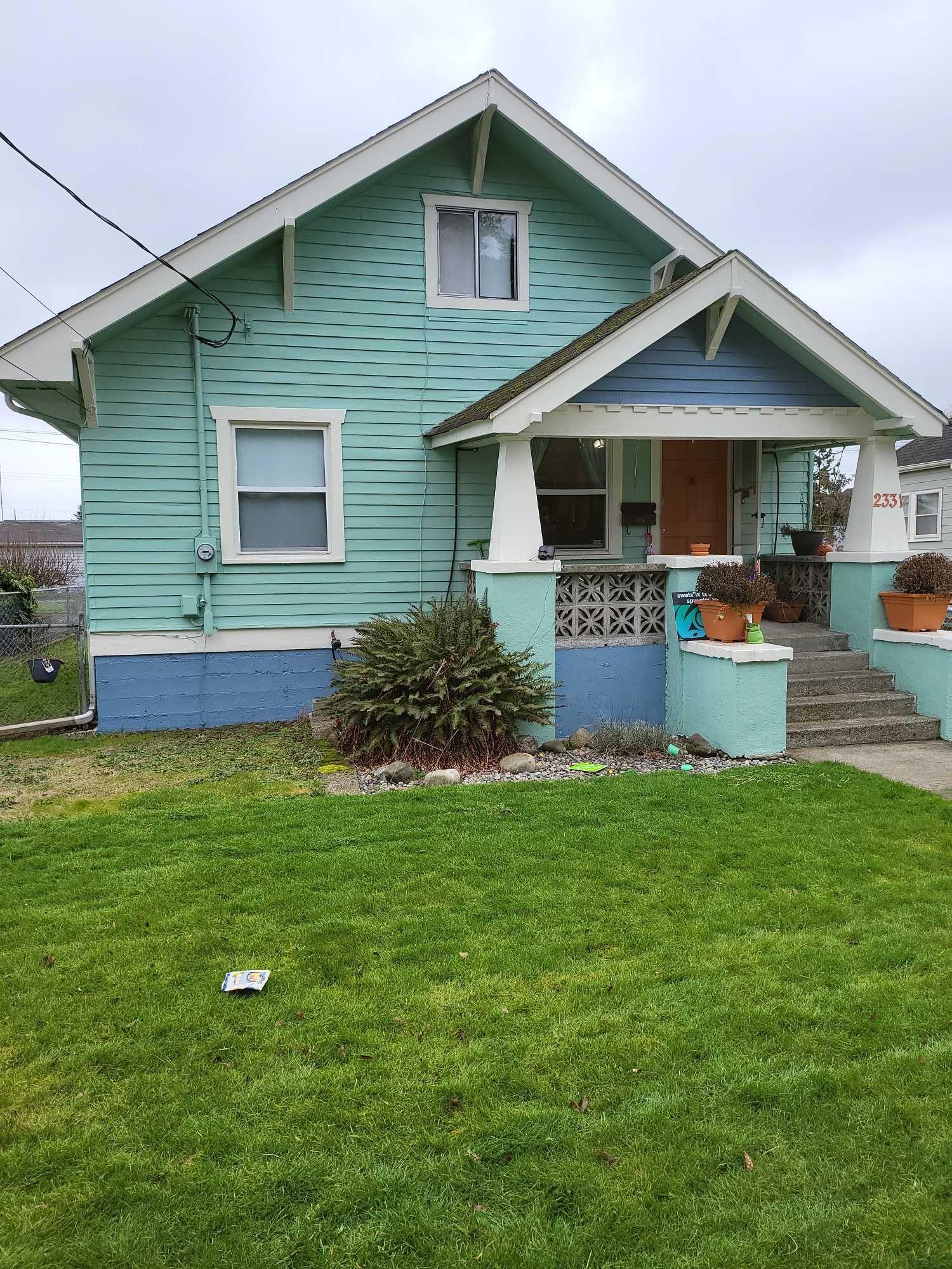 A small blue house with a large lawn in front of it.