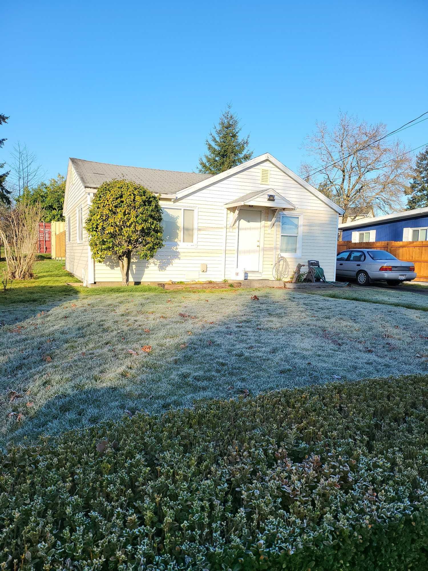 A small white house with a car parked in front of it.