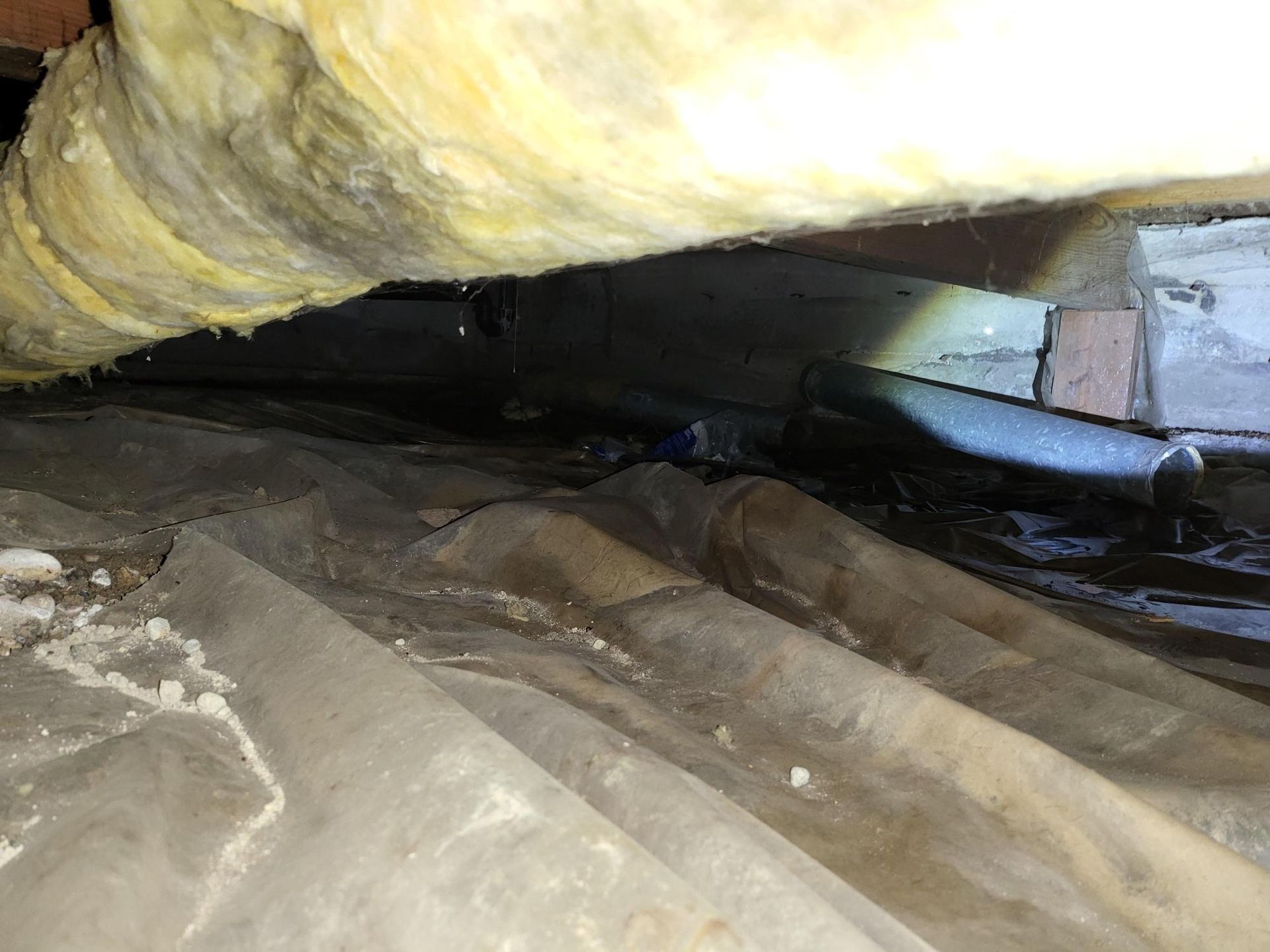 There is a lot of insulation in the crawl space of a house.