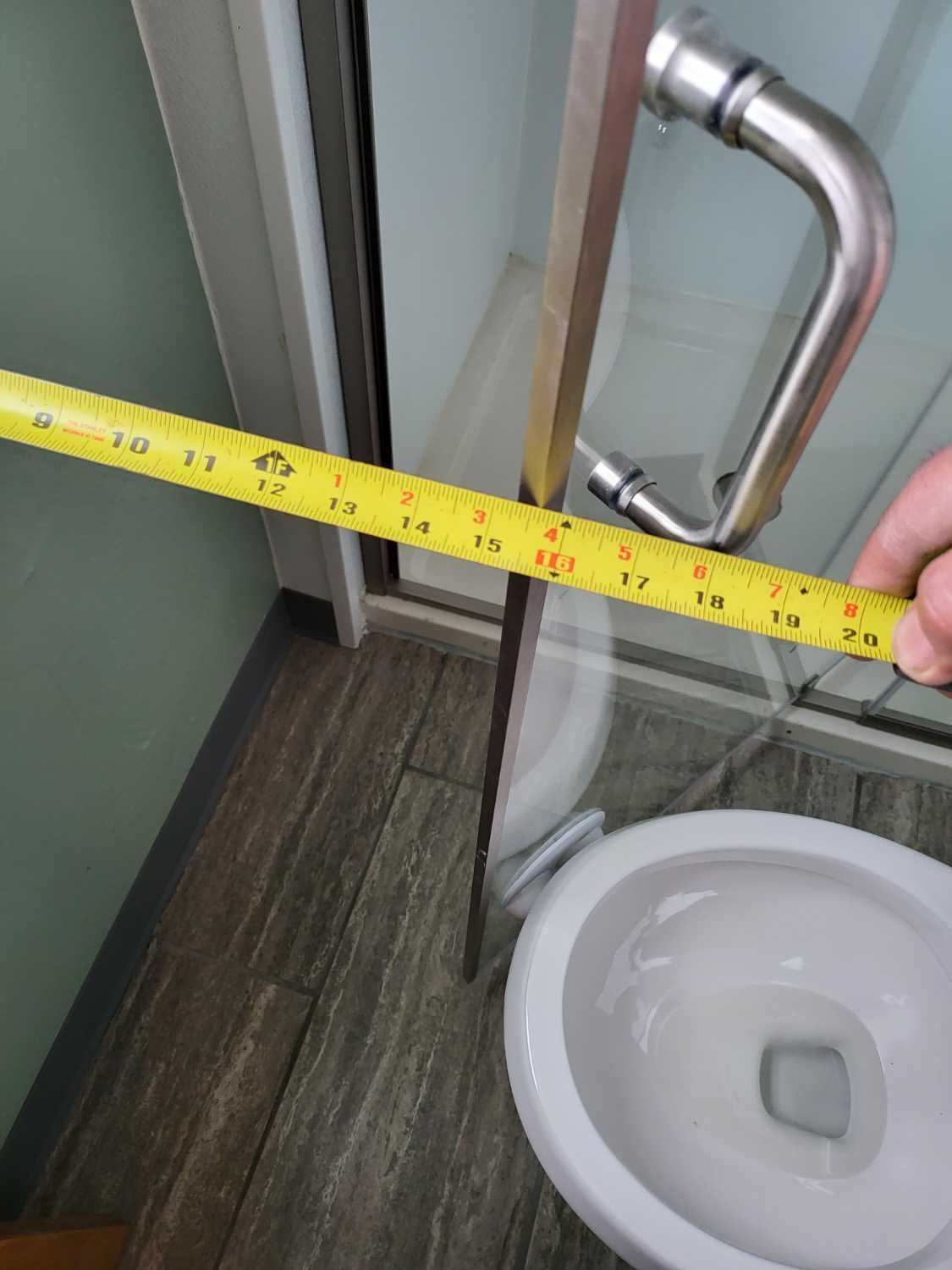 A person is measuring a toilet with a tape measure.