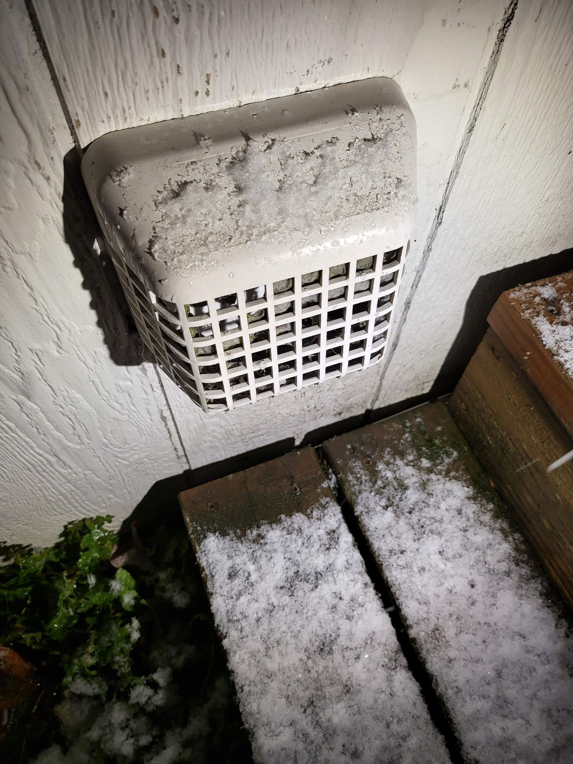 A drain on the side of a building with snow on it