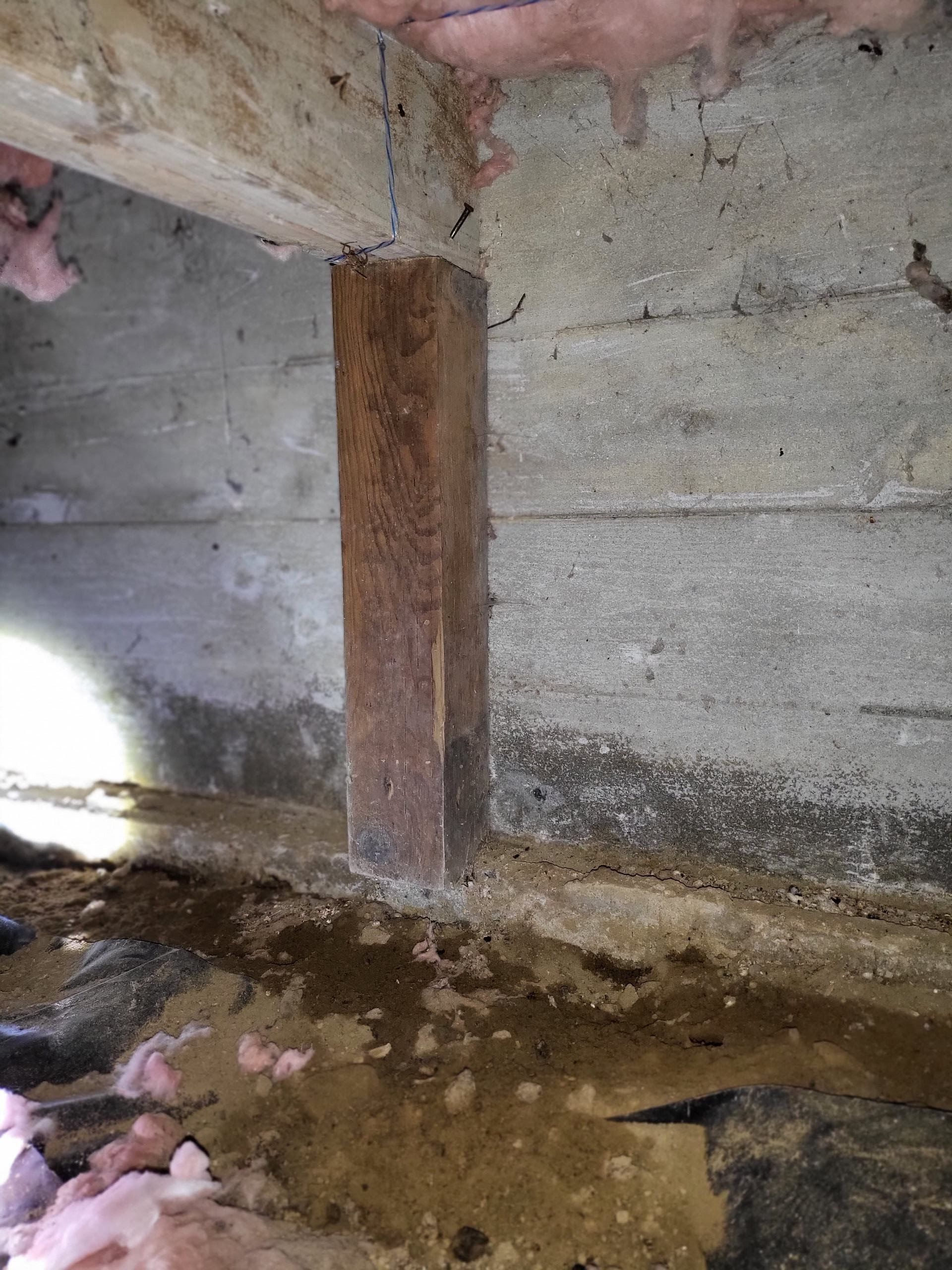 A close up of a wooden post in a concrete wall.
