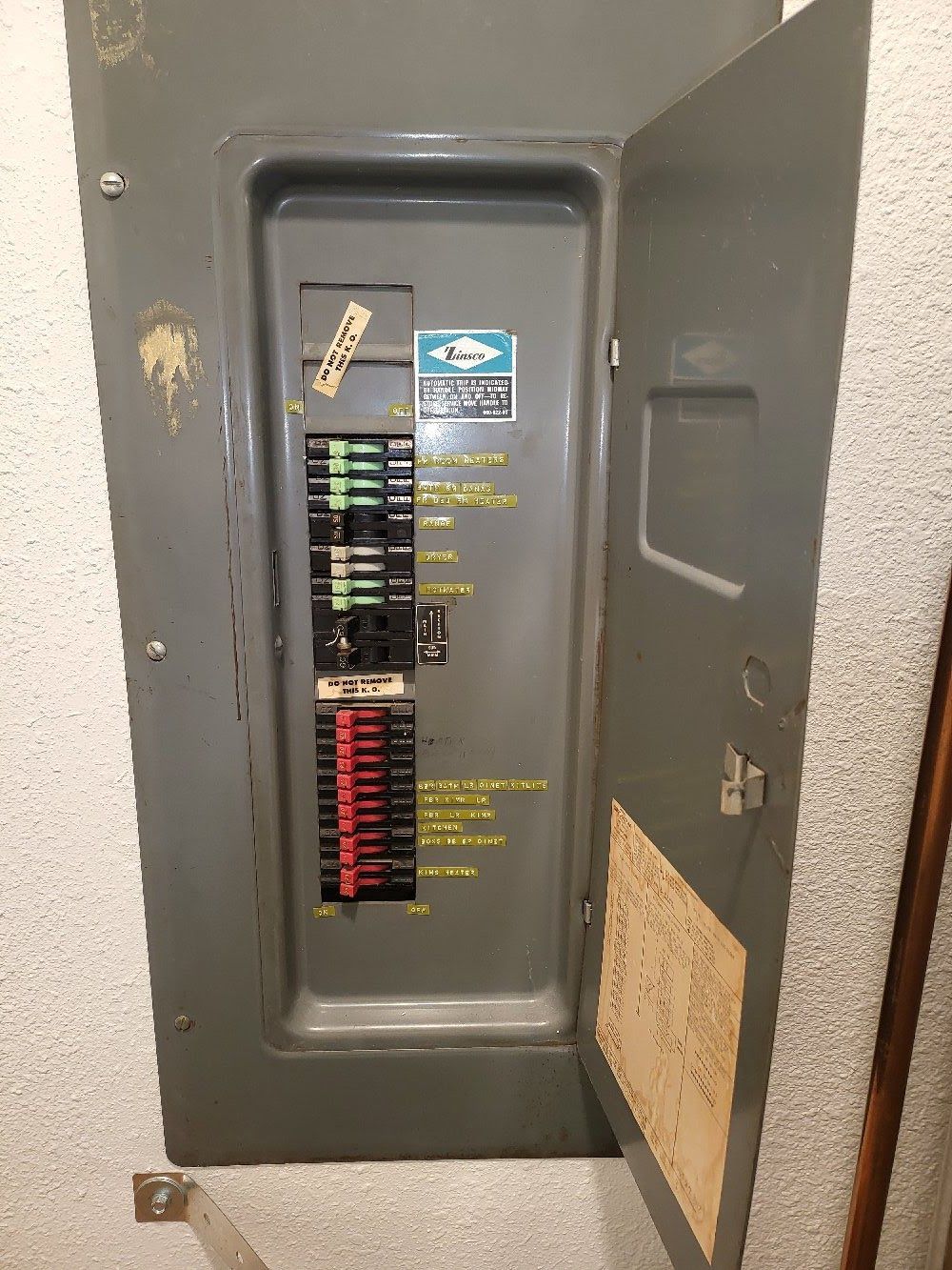 A gray electrical box with the door open on a wall.