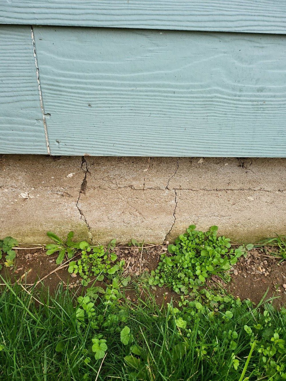 A house with a blue siding and a concrete foundation.
