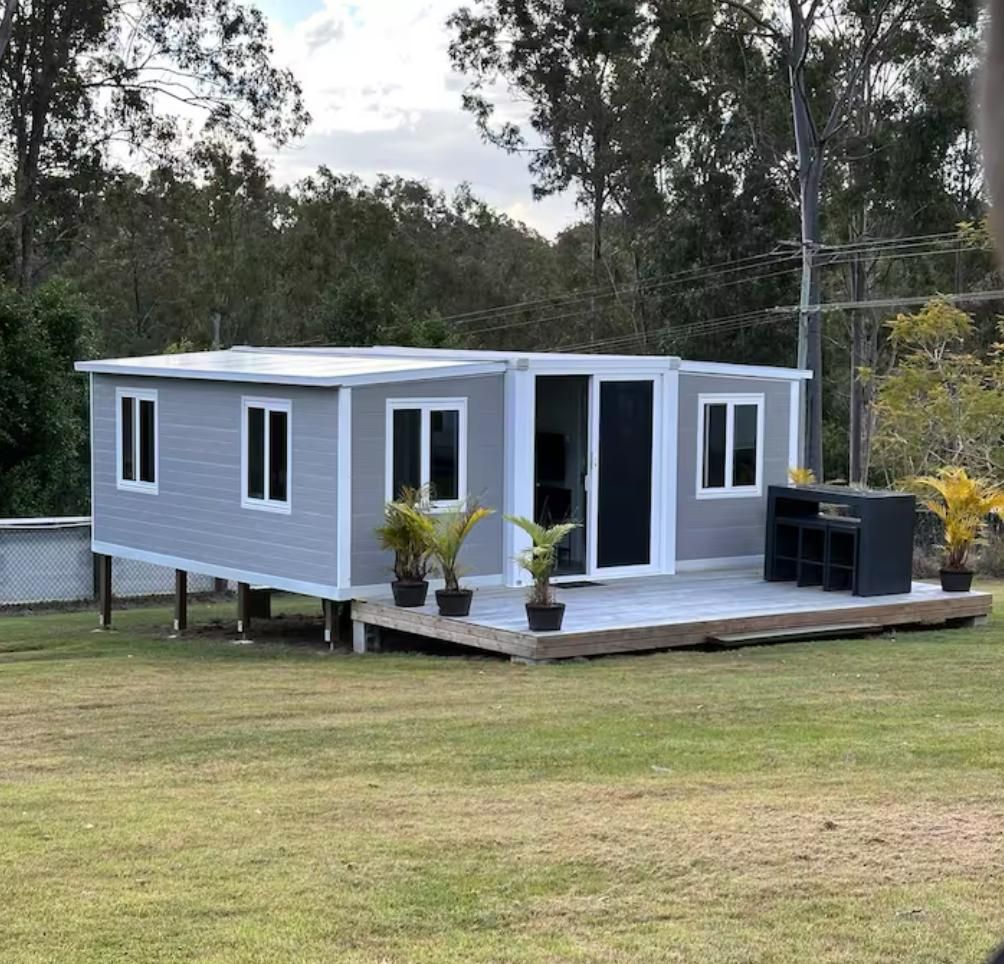Gray modular home with white trim and deck on grassy field — Expandable Housing in Inala, QLD