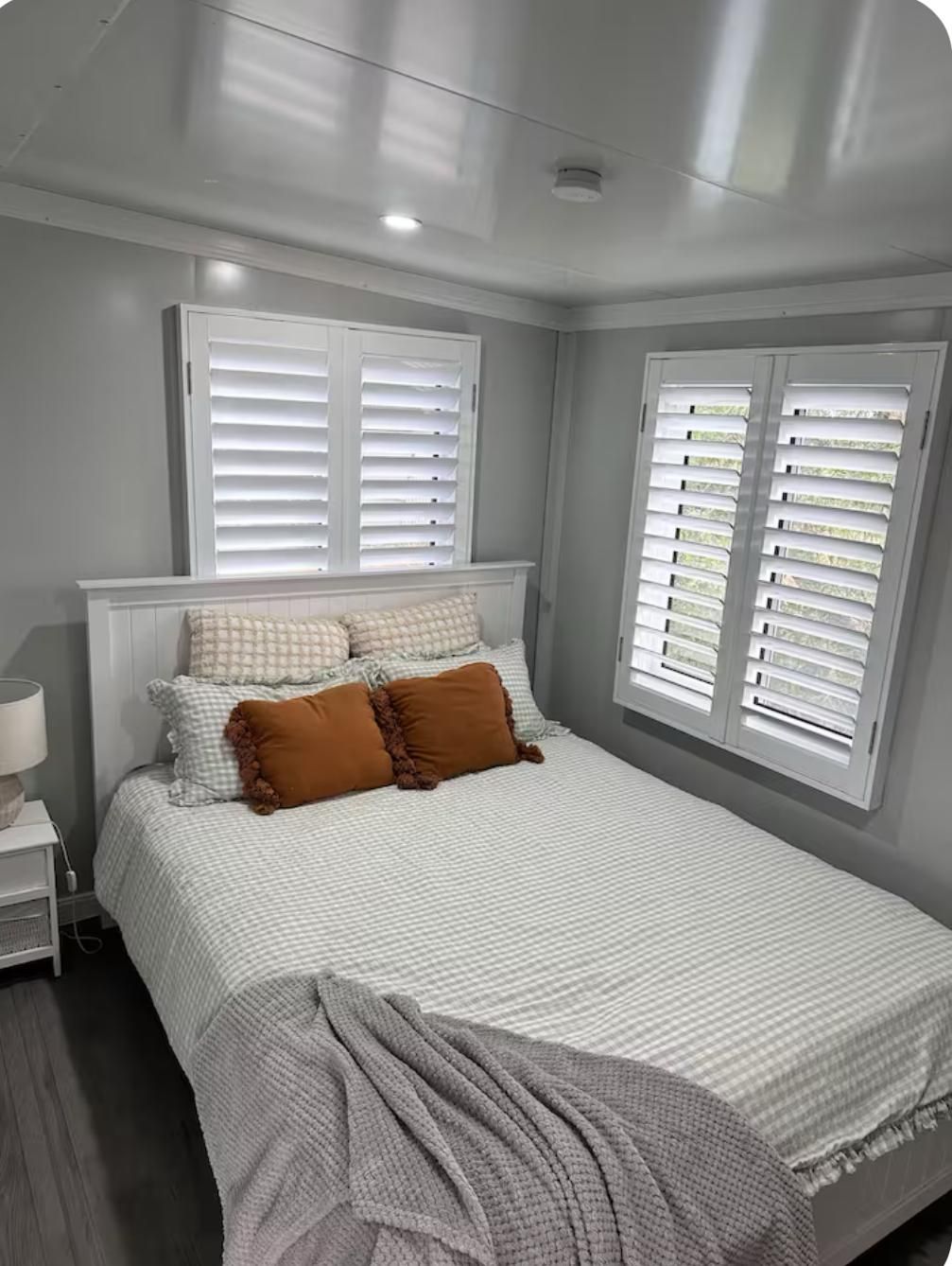 Bedroom With a White Bed, Orange Pillows, White Shutters — Expandable Housing in Inala, QLD