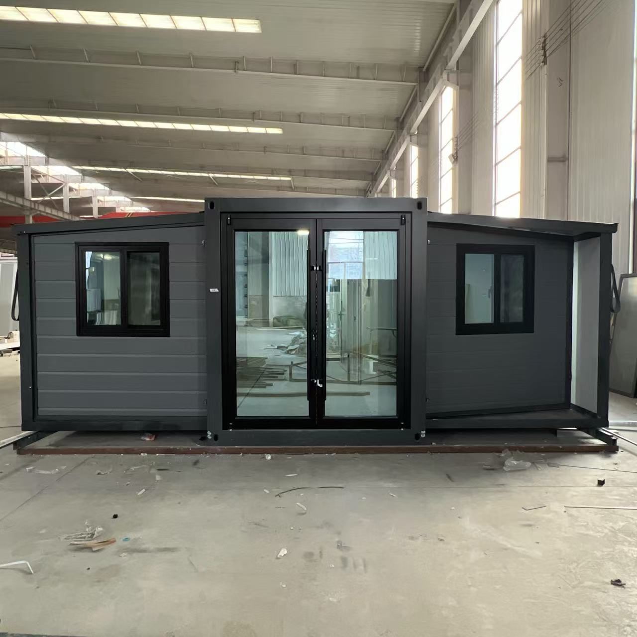 Gray modular building with glass doors and windows in a warehouse setting. — Expandable Housing in Inala, QLD