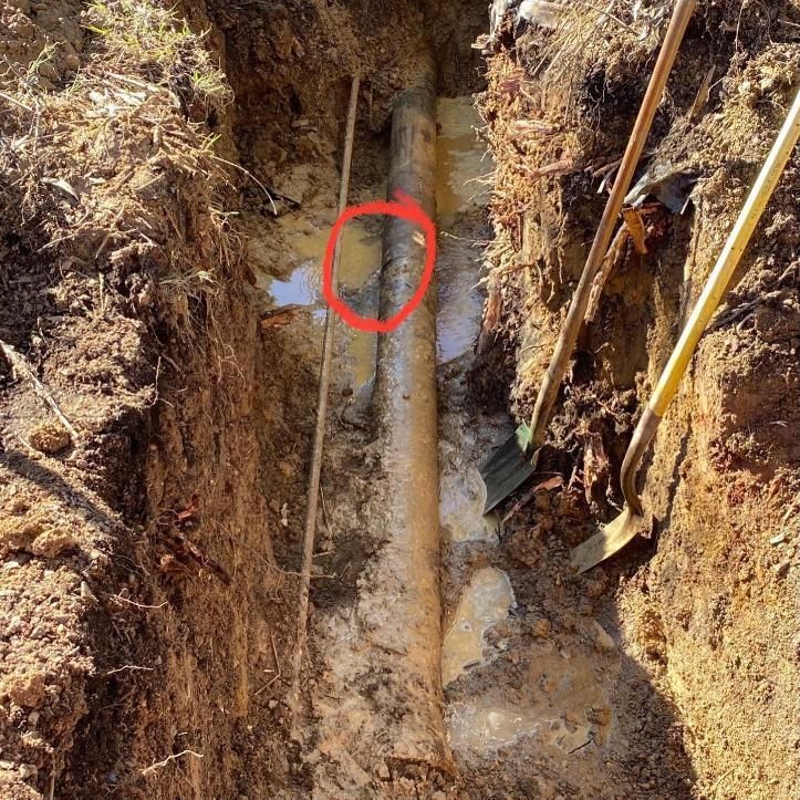 A Trench With a Buried Pipe Highlighted by a Red Circle — Huddo's Plumbing Service in Port Stephens, NSW
