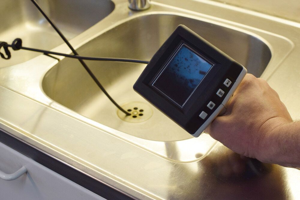 Hand Holding a Camera Inspecting a Kitchen Sink Drain — Huddo's Plumbing Service in Wallalong, NSW