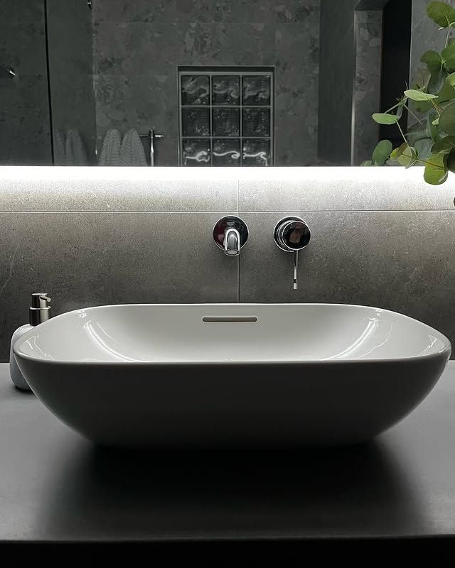 Oval White Sink With Wall-mounted Faucets, and Under-mirror Lighting — Huddo's Plumbing Service in Wallalong, NSW