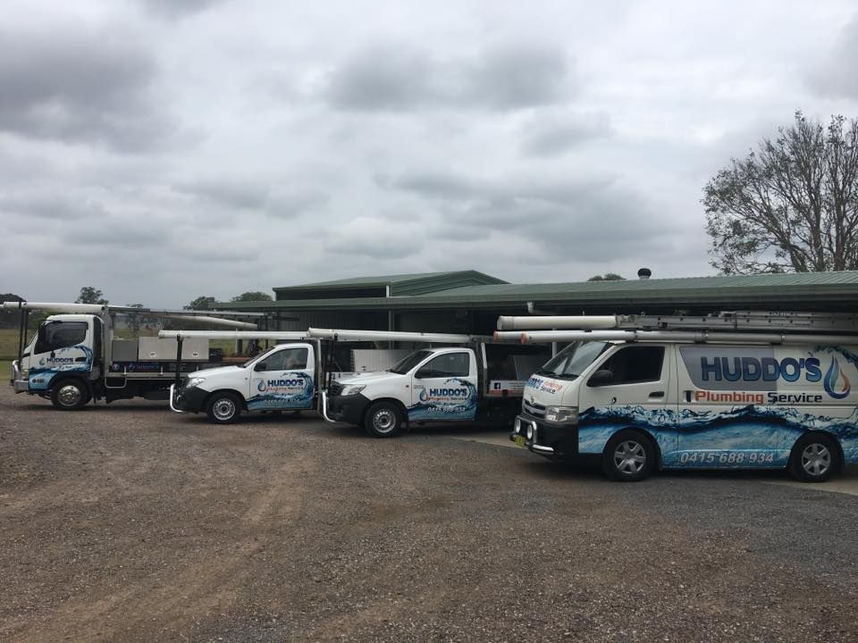 Four White Service Vehicles Parked Under a Covered Area — Huddo's Plumbing Service in Wallalong, NSW