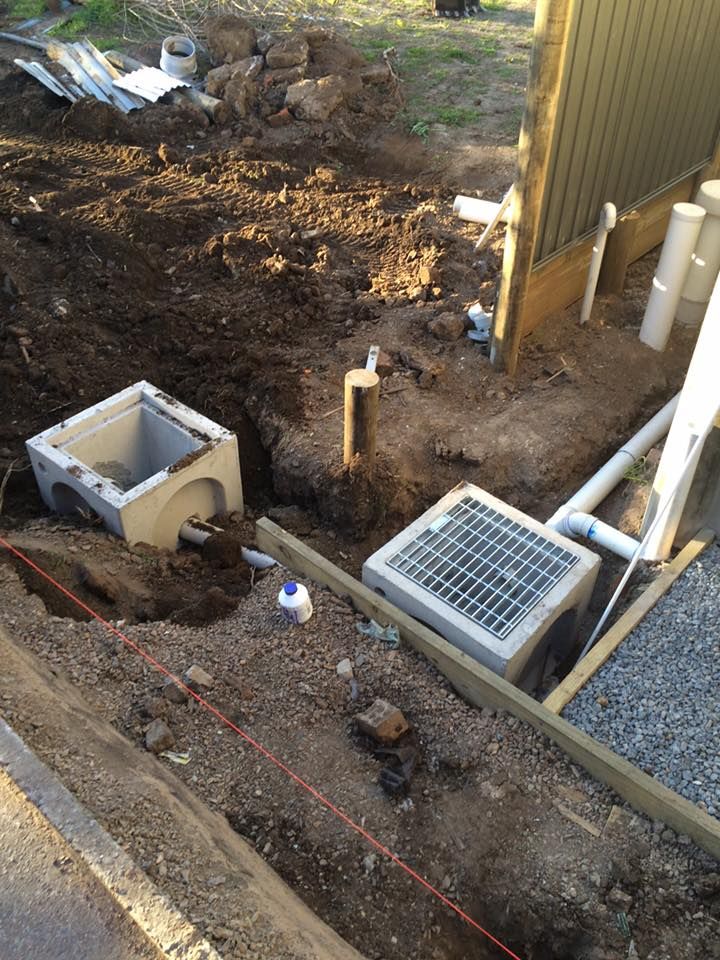 Two Concrete Drainage Pits, Pipes, and Trench Work Near a Building — Huddo's Plumbing Service in Newcastle, NSW