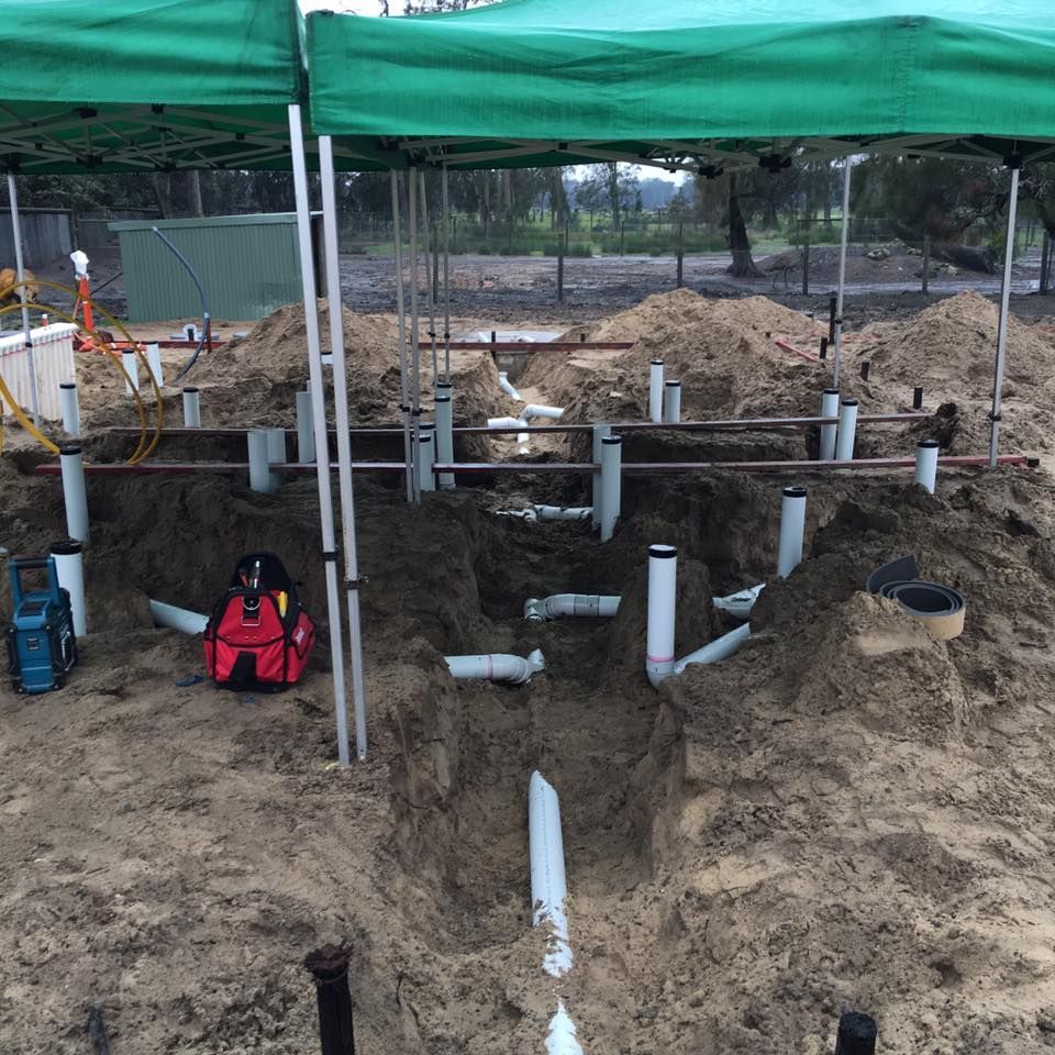 Plumbing Work in Progress in Dirt Trenches Under a Green Canopy — Huddo's Plumbing Service in Wallalong, NSW