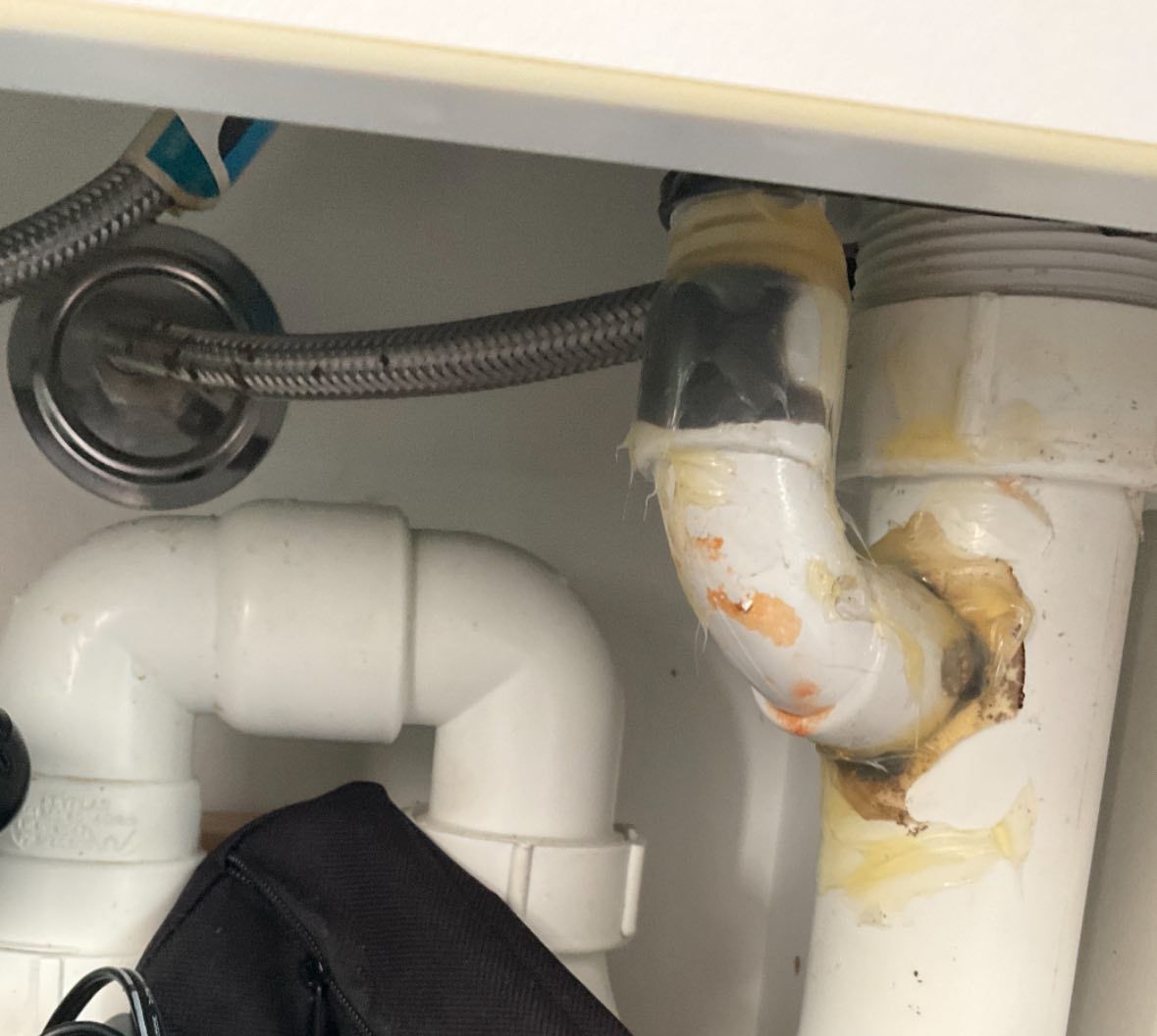 White Sink Pipes With Yellow Adhesive Tape, Under a Cabinet — Huddo's Plumbing Service in Newcastle, NSW
