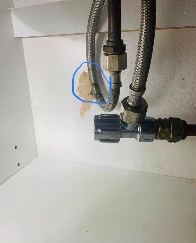 Pipes Under a Sink With a Damaged Wall. Area Circled in Blue — Huddo's Plumbing Service in Port Stephens, NSW