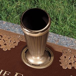 A brass vase is sitting on top of a grave.