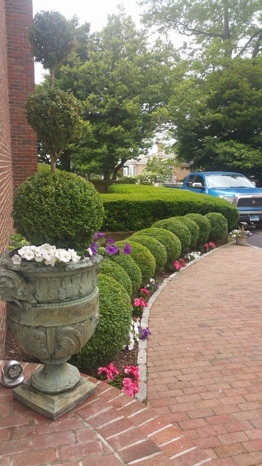 A brick walkway with a planter filled with flowers and bushes.