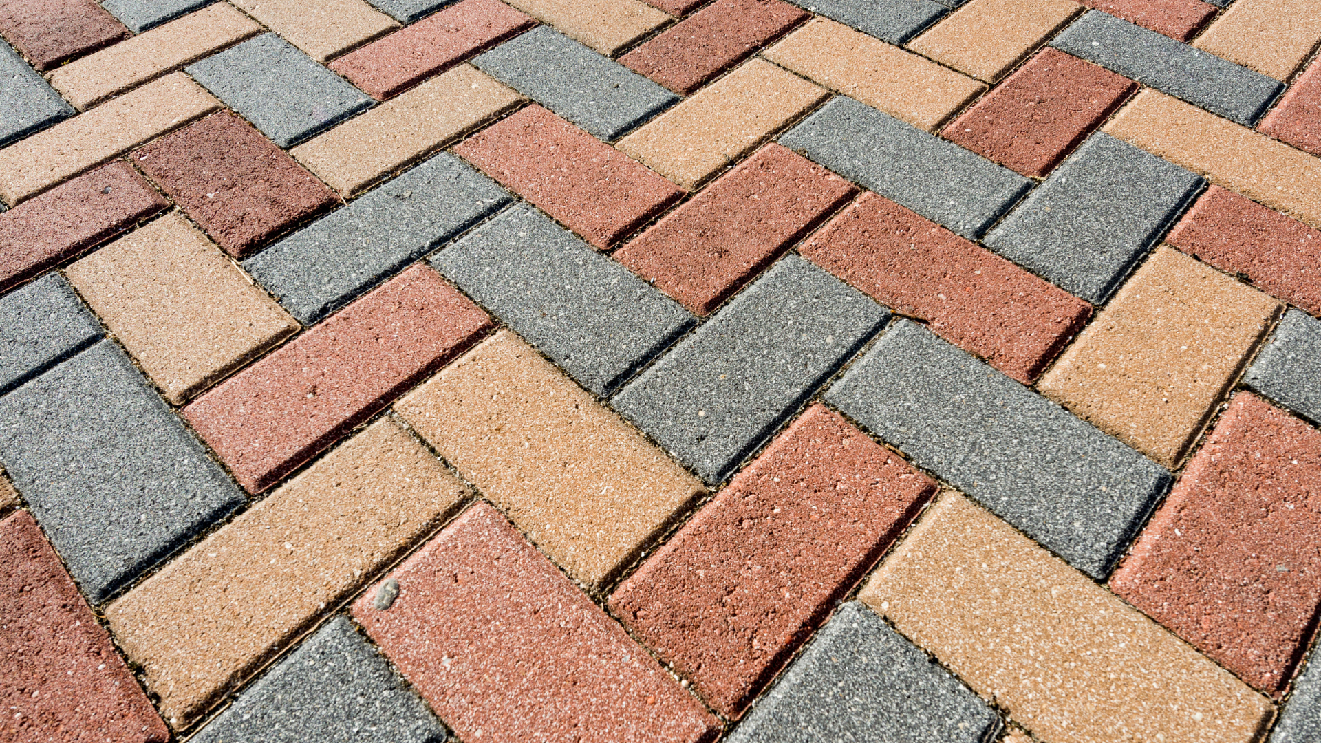 A close up of a brick pavement with a herringbone pattern.