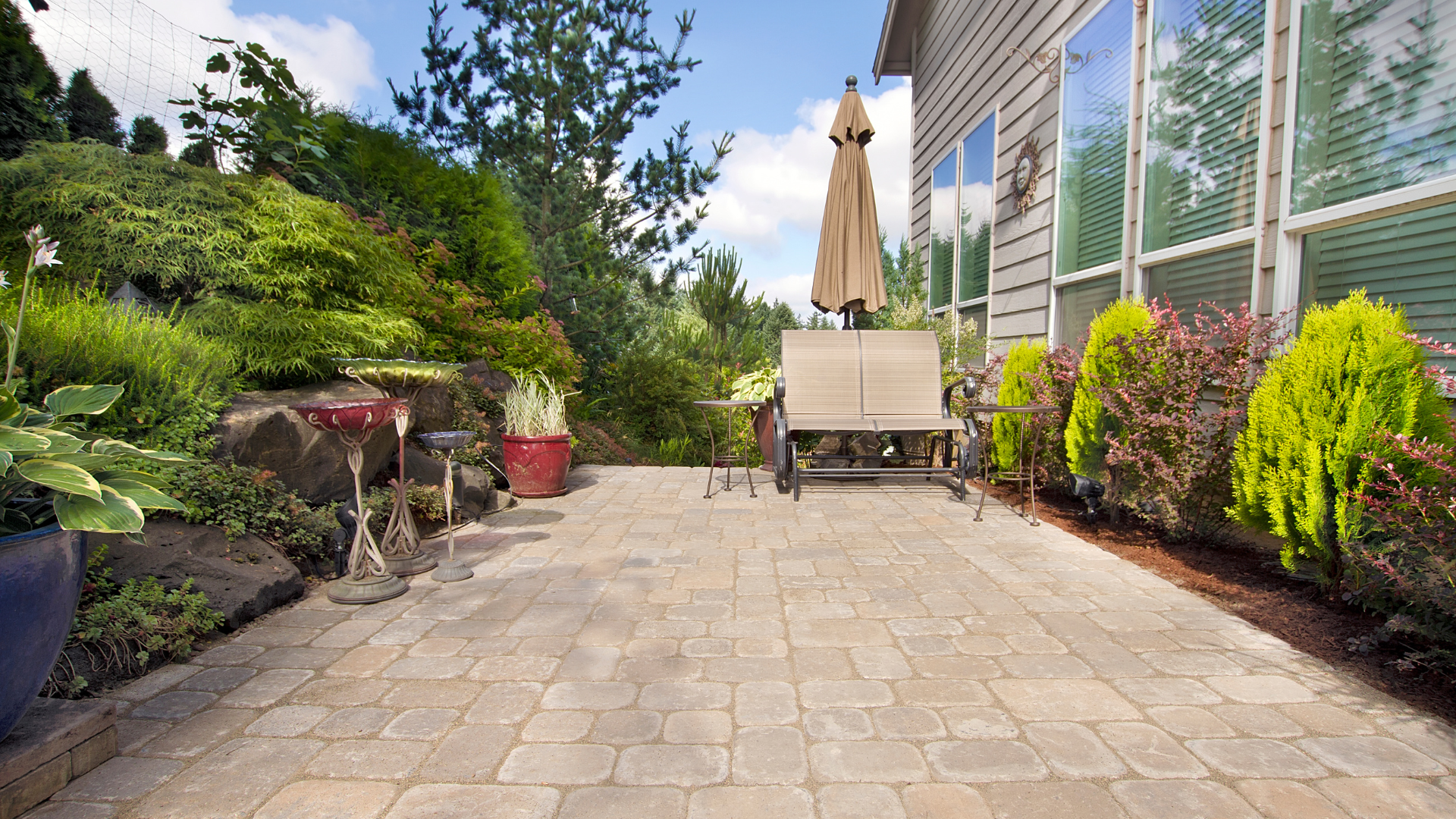 A patio with a table and chairs and an umbrella in front of a house.
