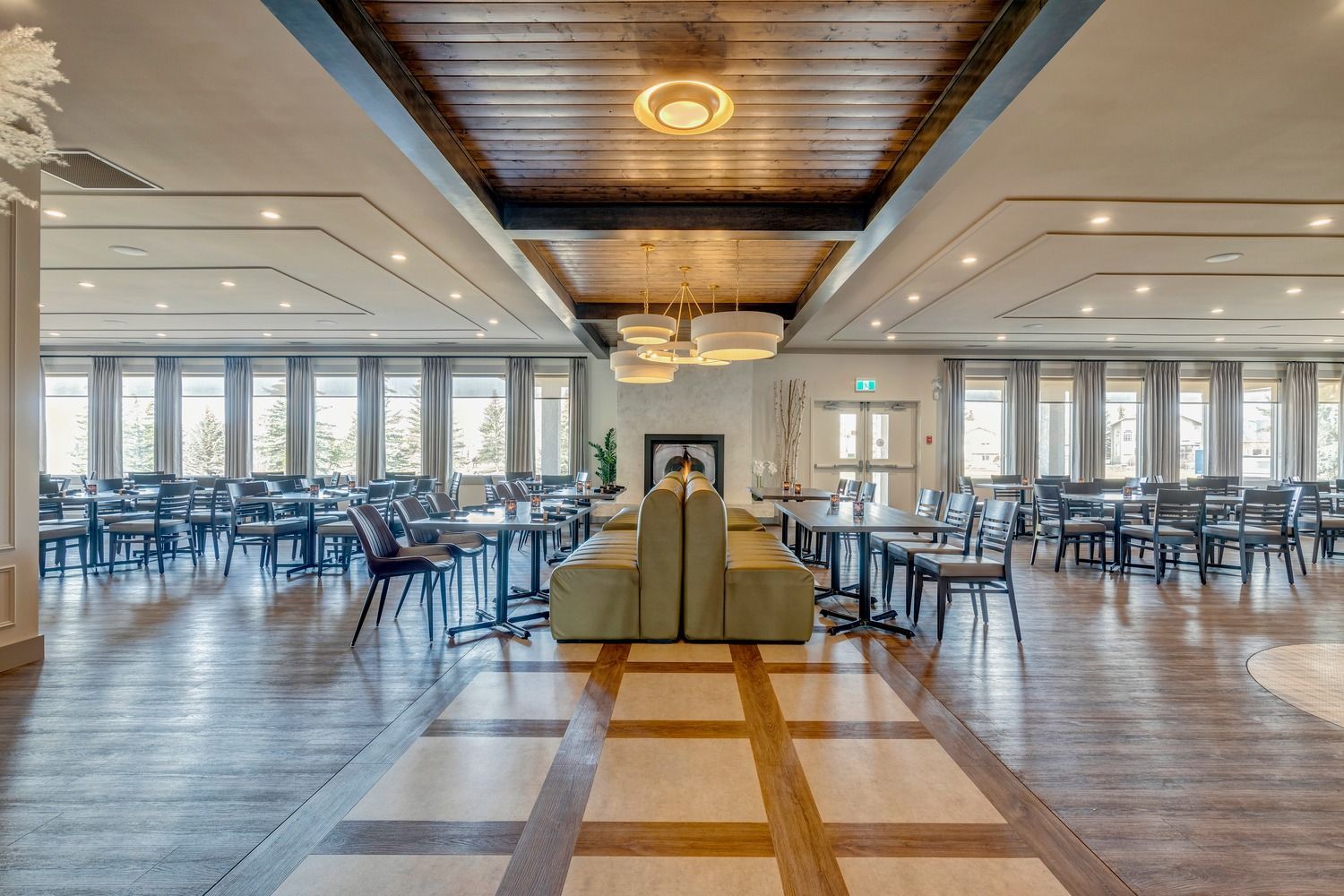 A spacious dining hall with rows of tables and chairs, wood floors, a wooden ceiling, and a central seating booth.