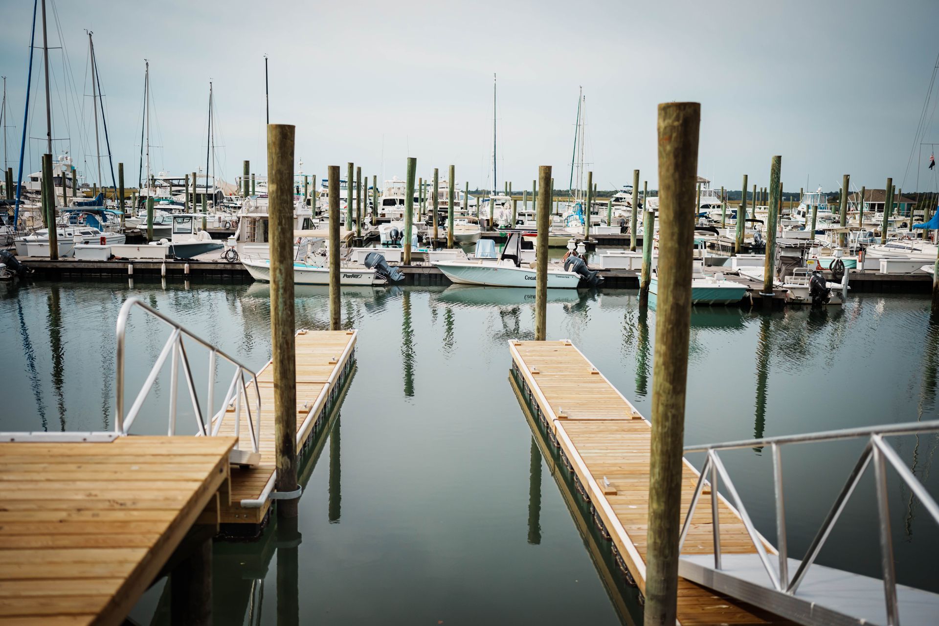 Boats are docked at a marina with a wooden dock in the foreground