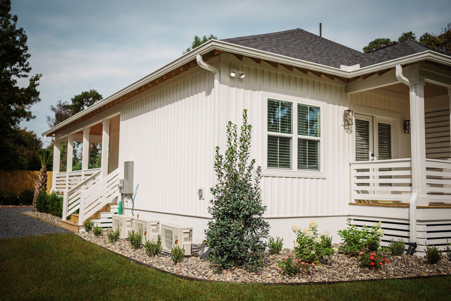 A white house with a gray roof and green shutters