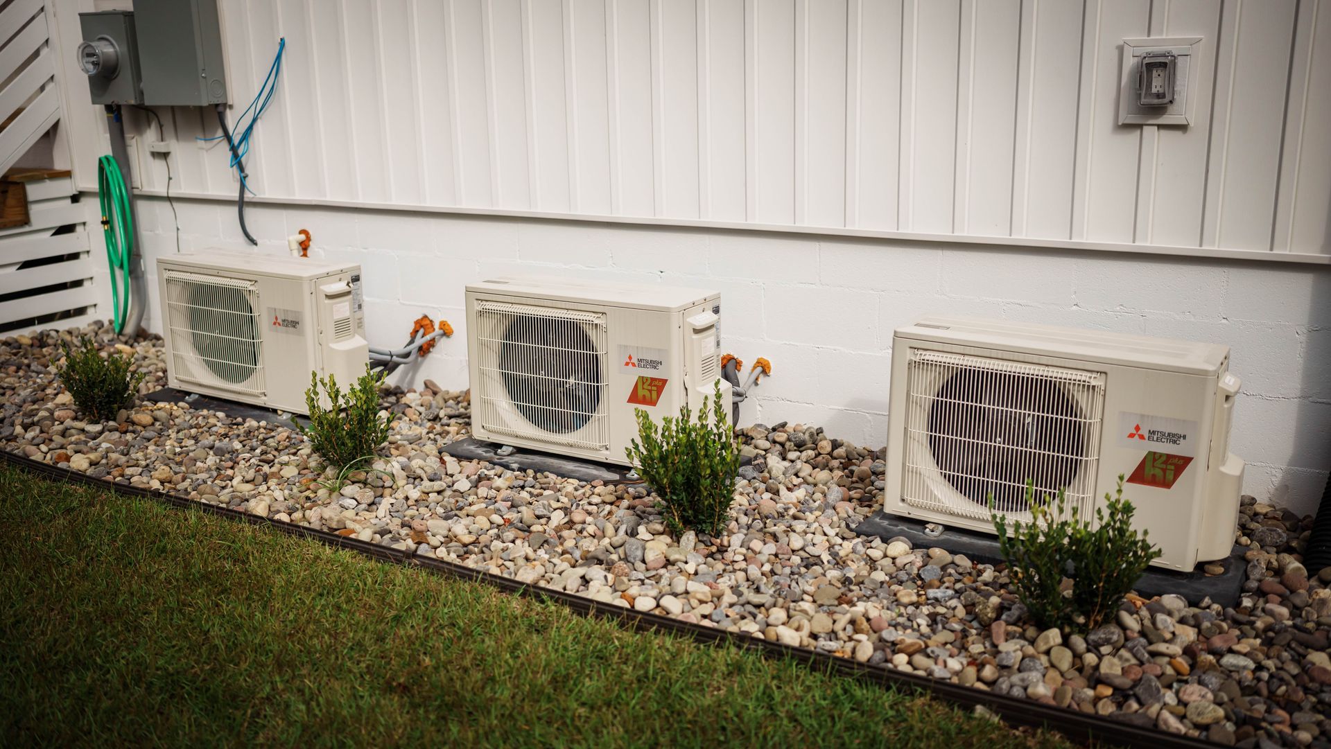 A row of mitsubishi air conditioners are sitting in a rock garden