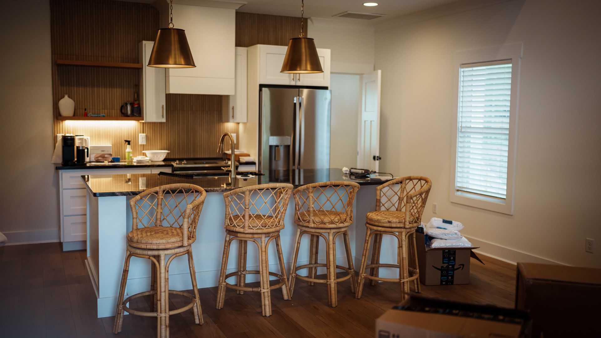 A kitchen with wicker bar stools and a stainless steel refrigerator