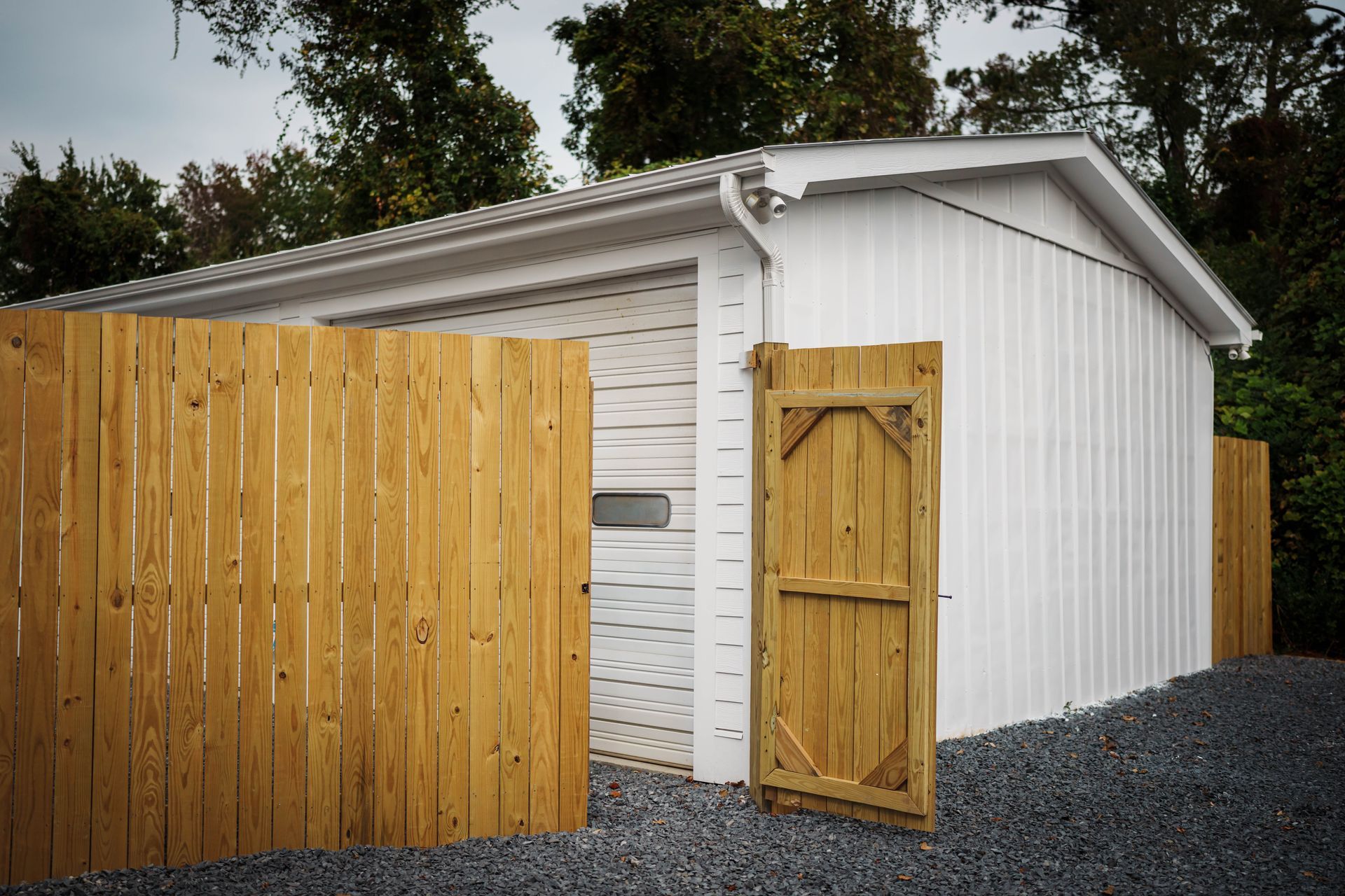 A white garage with a wooden fence around it