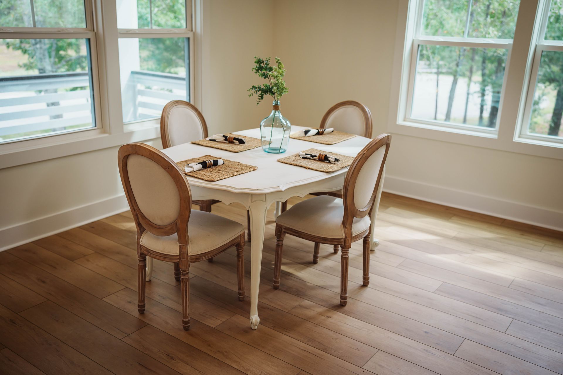 A dining room table with four chairs and a vase of flowers on it