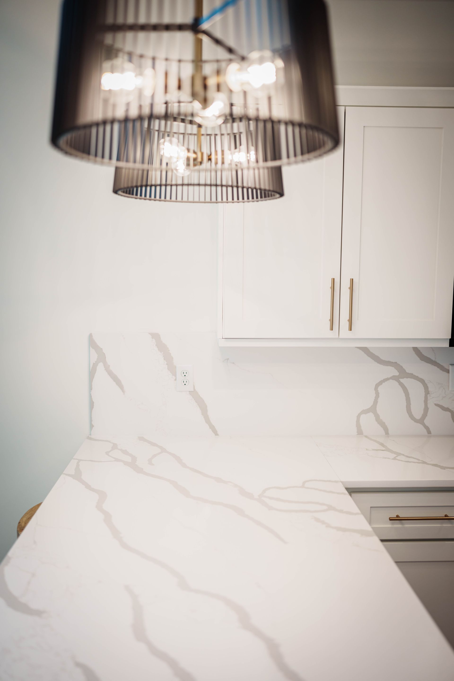 A kitchen with a marble counter top and a chandelier hanging from the ceiling.
