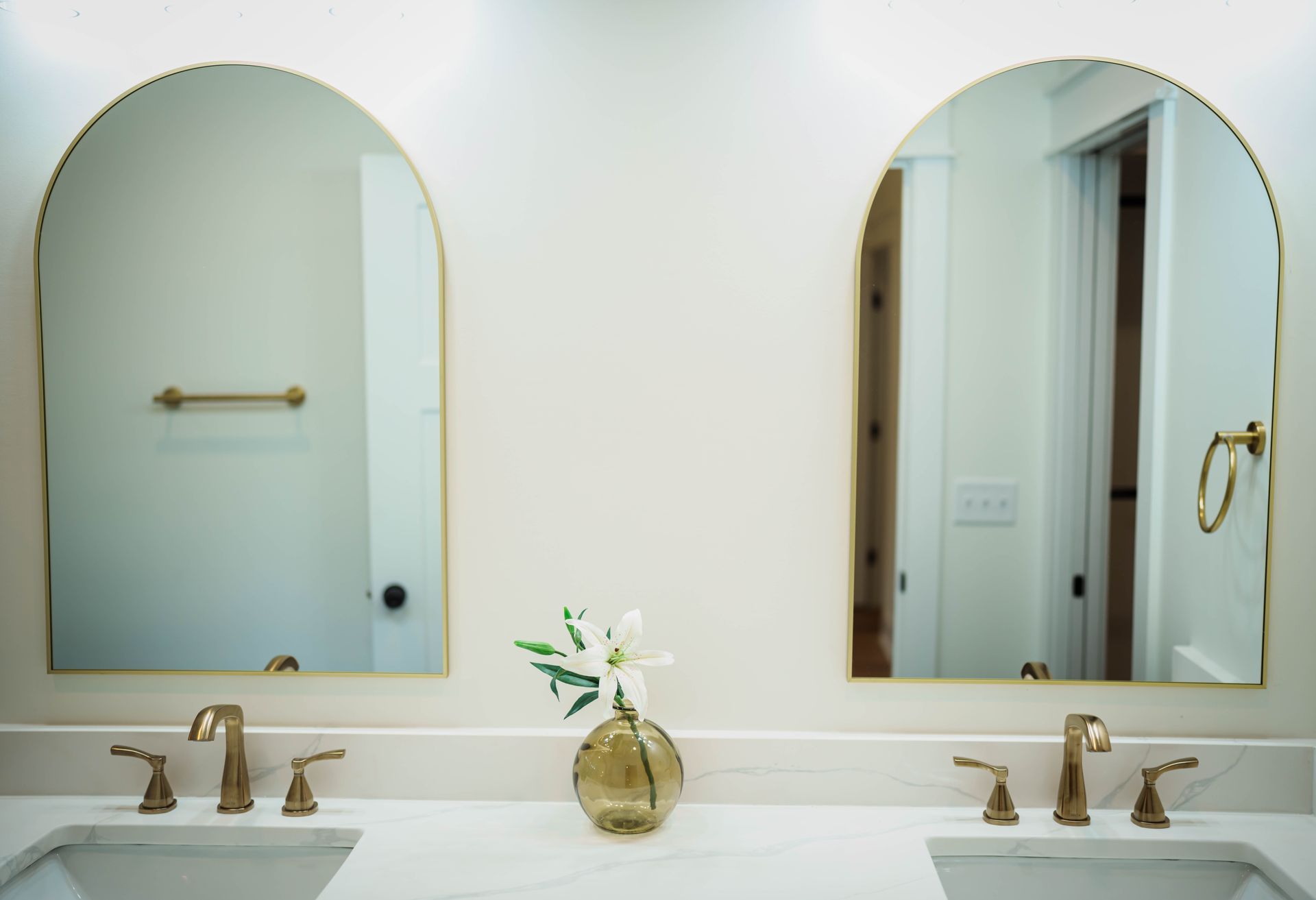 A bathroom with two sinks and two arched mirrors